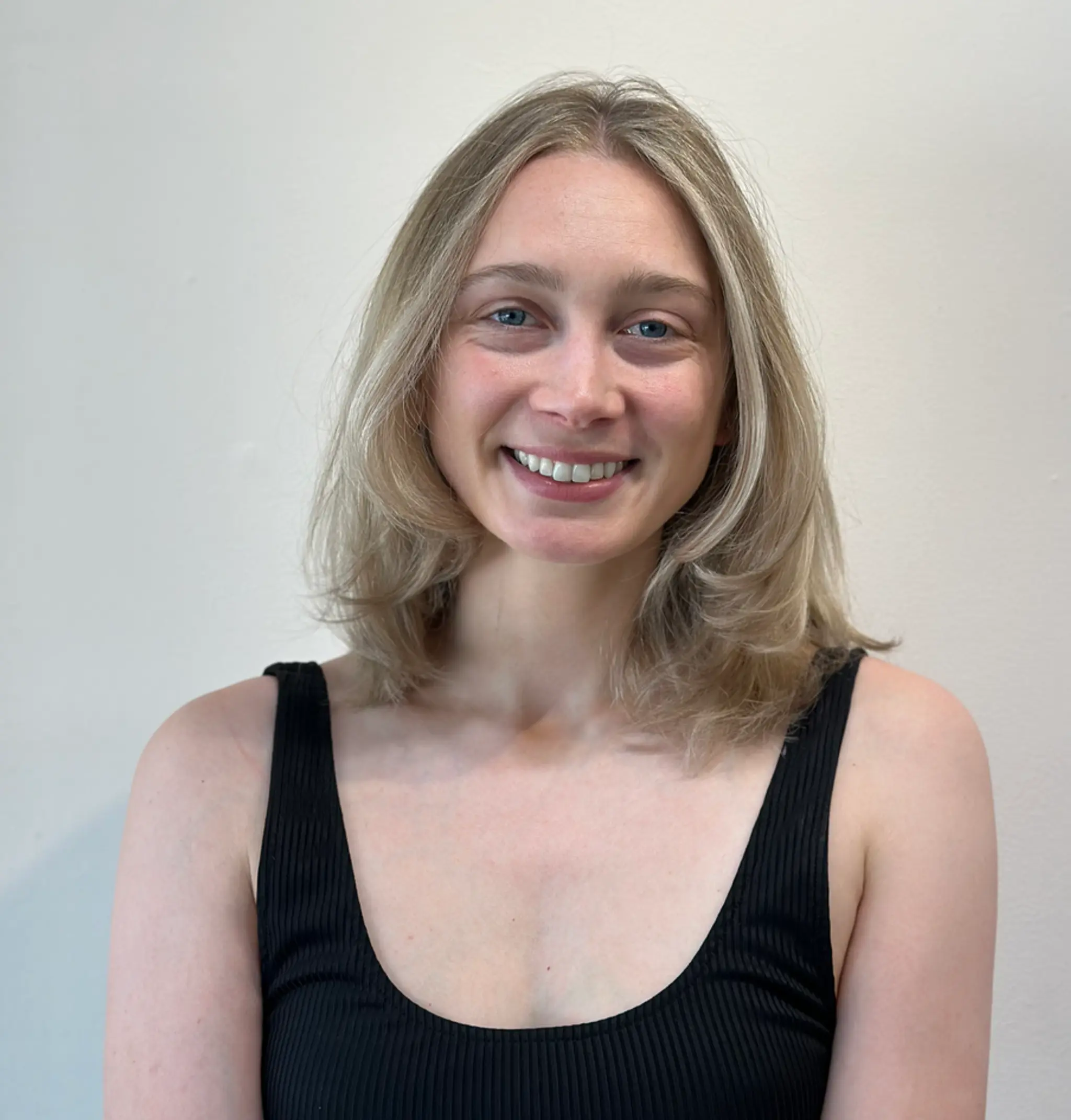 Medium-length light ash blonde hair with subtle layers and soft, natural waves, featuring a middle part and smooth finish.