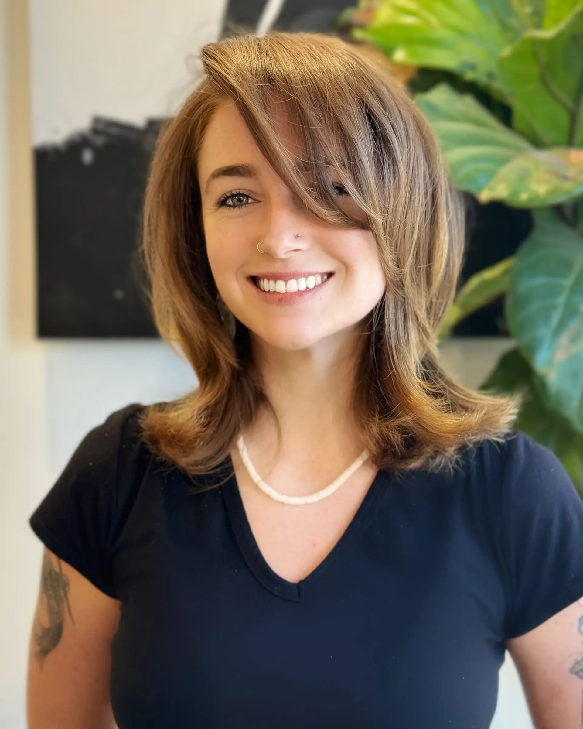 A 90s-inspired medium layered haircut featuring face-framing layers, swooping side-swept fringe, and bouncy blown-out flipped ends. 1
