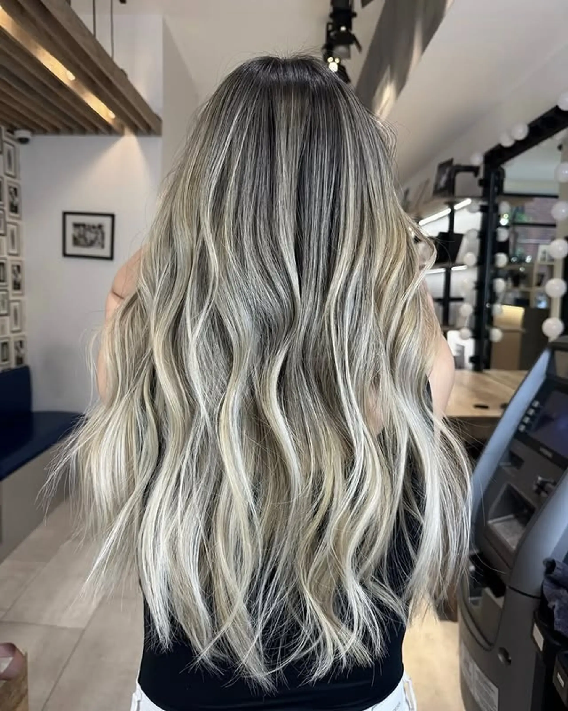 A beautiful wavy hairstyle with a balayage that transitions from dark roots to icy blonde tips. 1