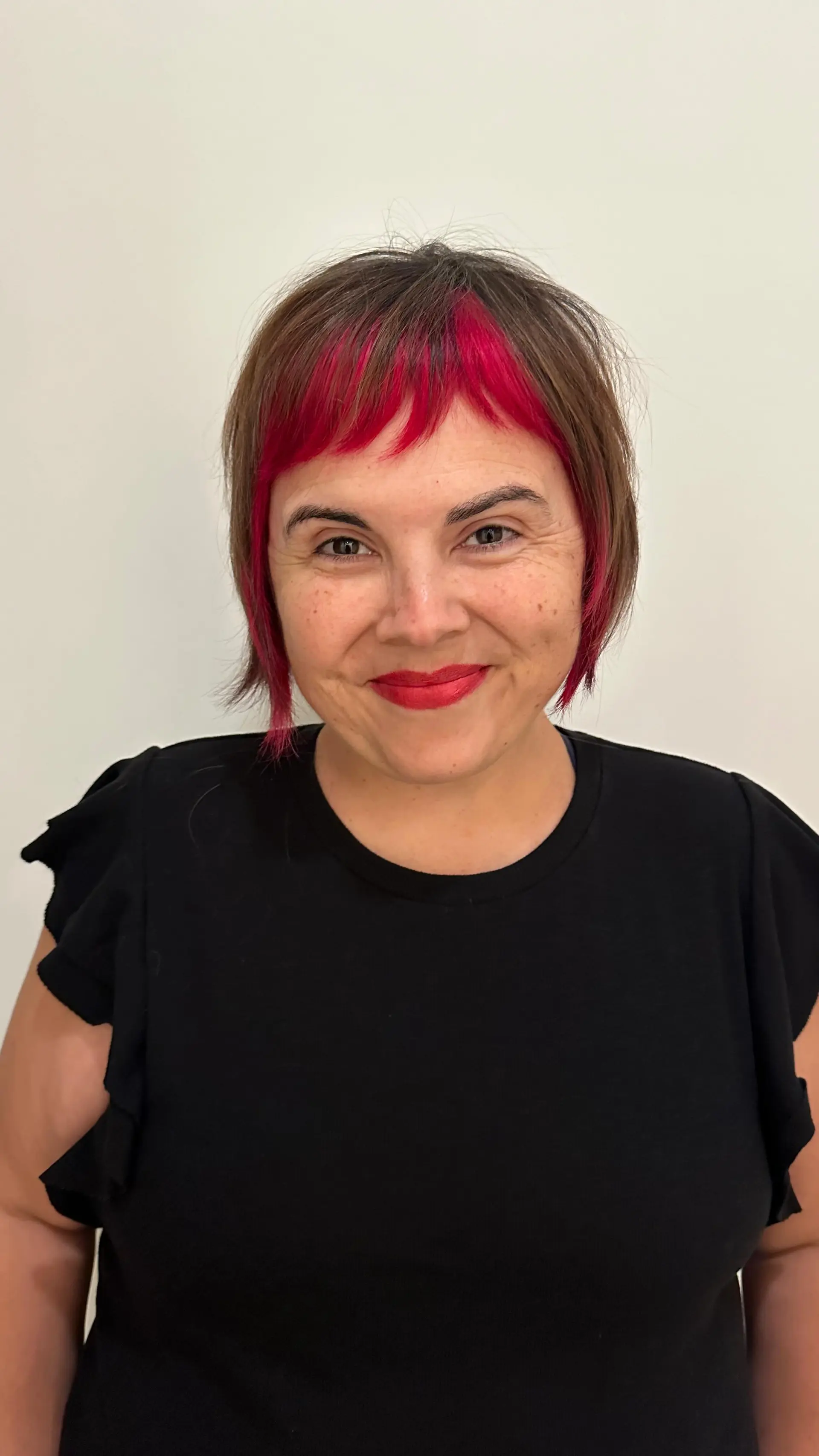 A textured short bob featuring piecey micro bangs and vibrant magenta color blocking framing the face. 1