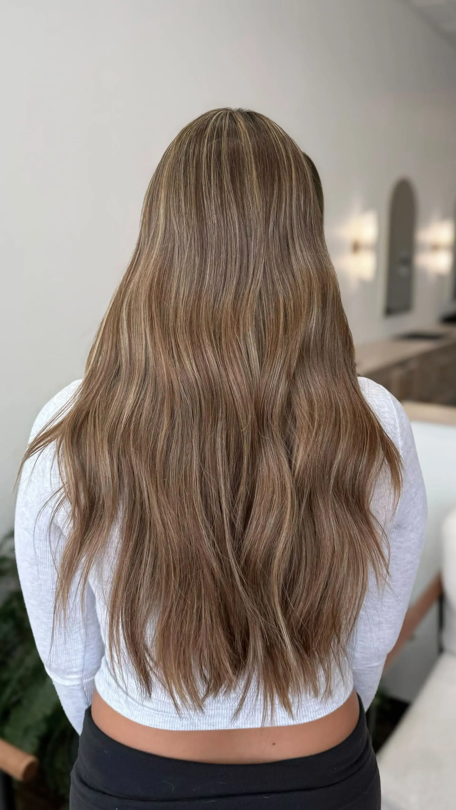 Long ash brunette hair styled with subtle waves, featuring fine blonde balayage highlights throughout. 1
