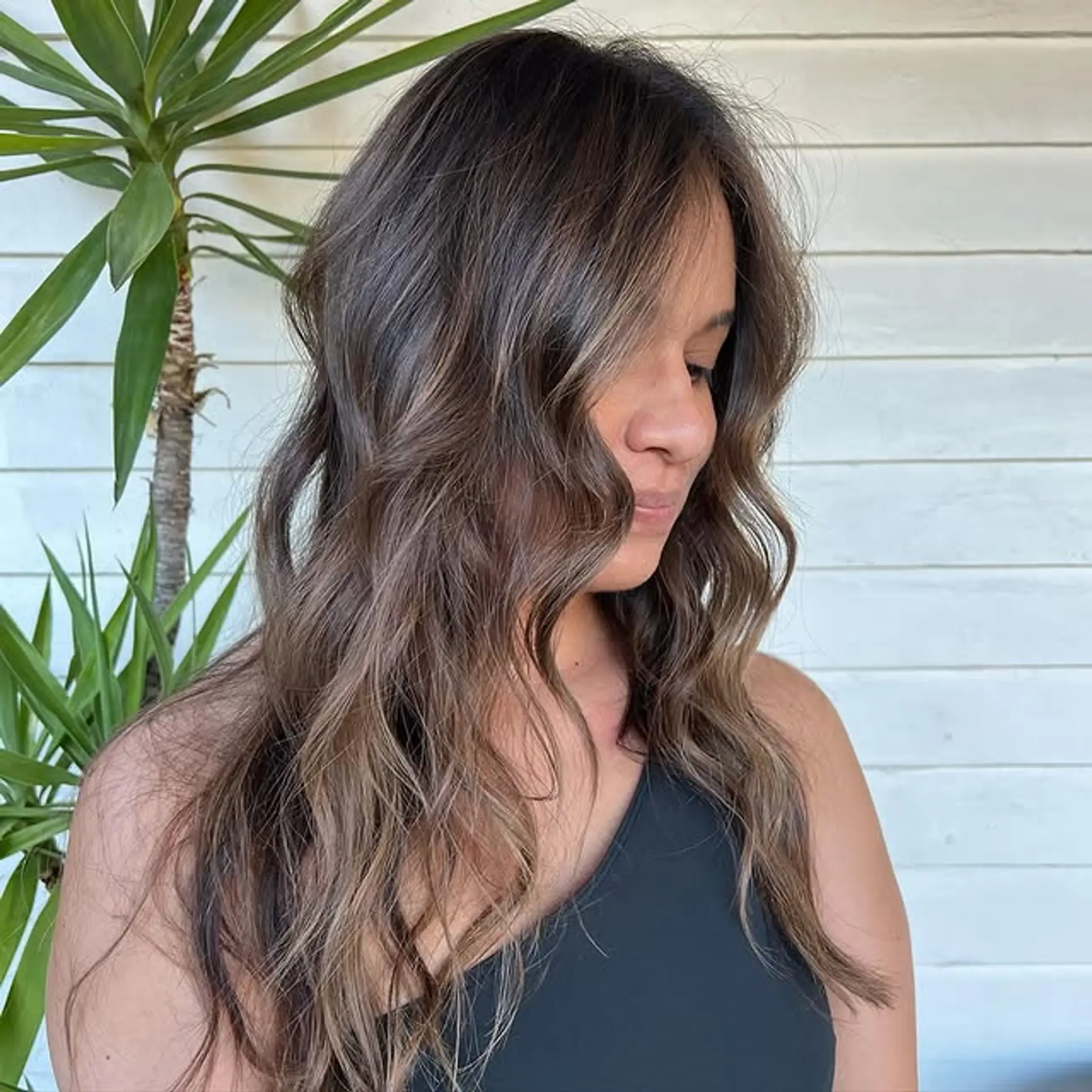 Long, wavy hair with a balayage color melt from dark roots to blonde ends. 1