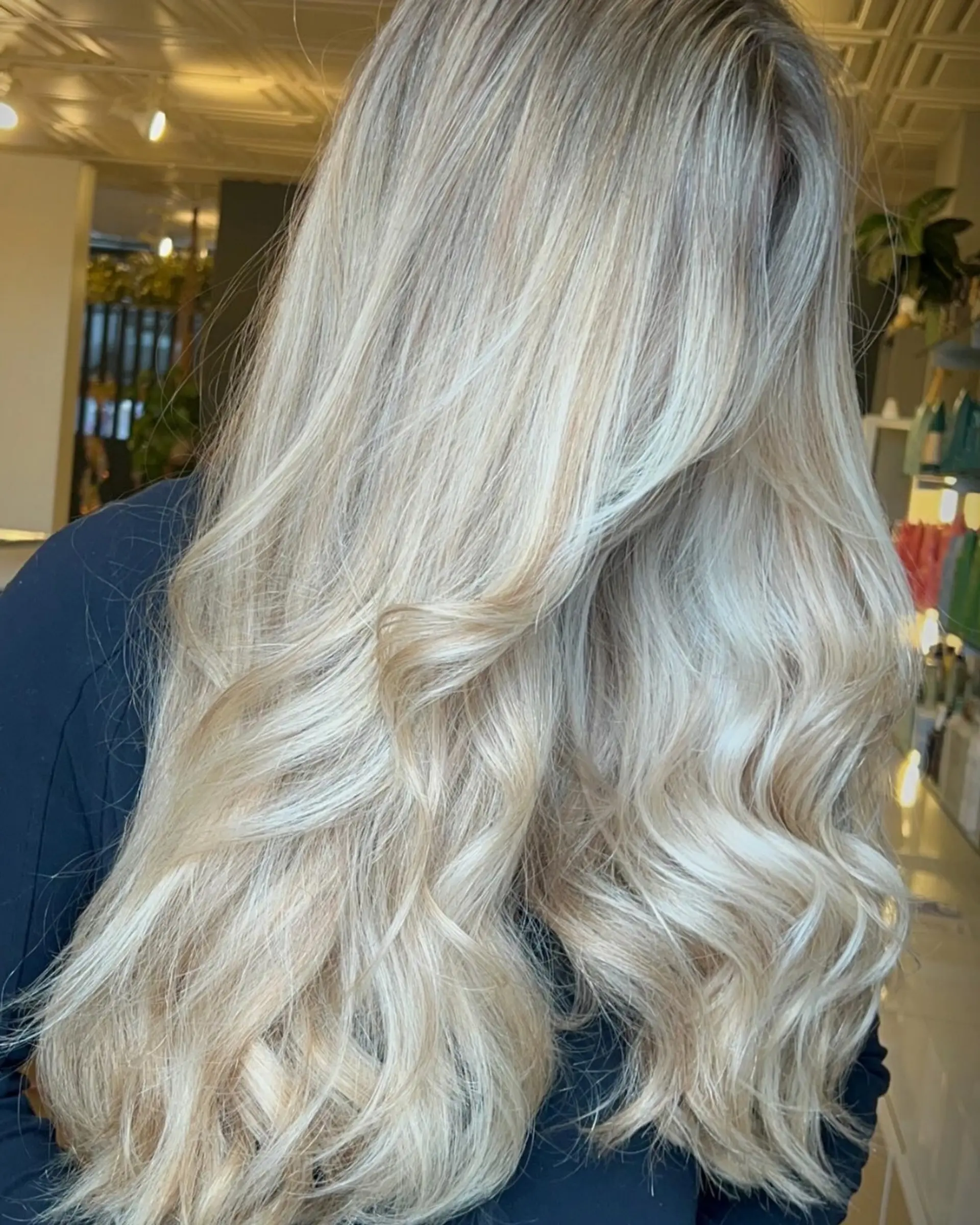 Long, flowing bright blonde hair styled with soft, loose waves and gentle dimension throughout. 1