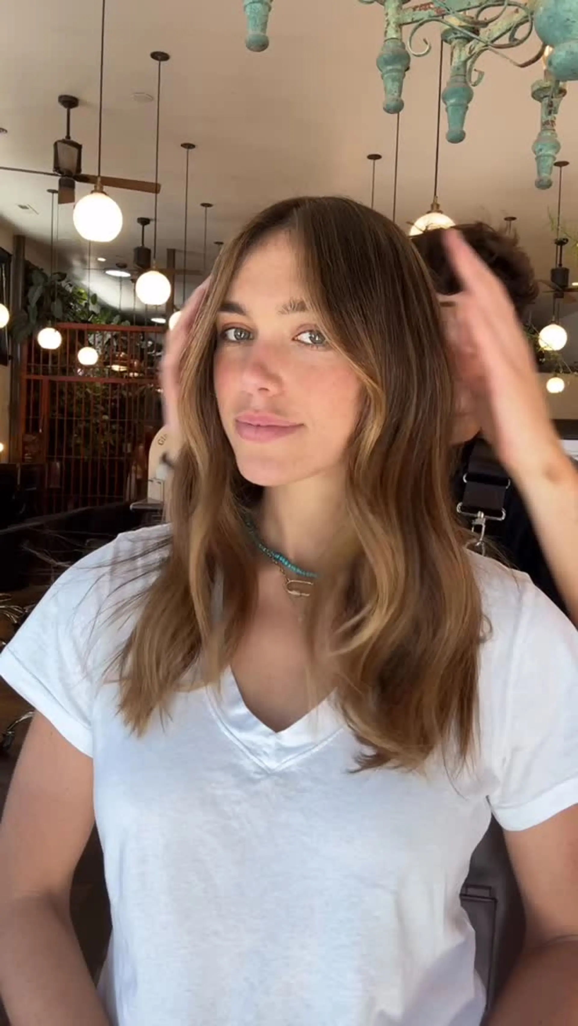 Medium-length brunette hair enhanced with sunkissed golden highlights and styled into soft, effortless waves. 1