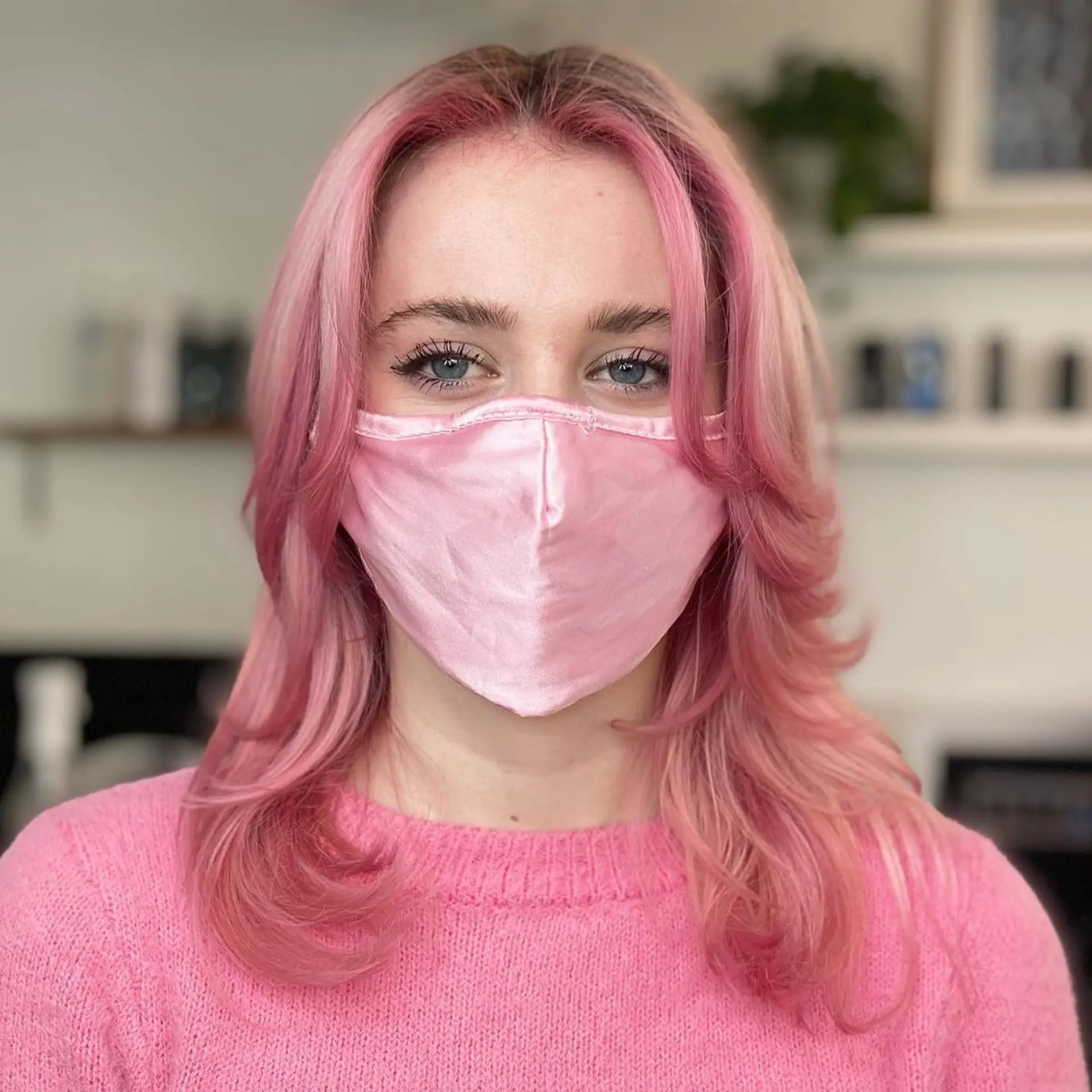 A medium-length, layered hairstyle with soft waves. The hair is colored pastel pink, creating a playful and stylish look. 1