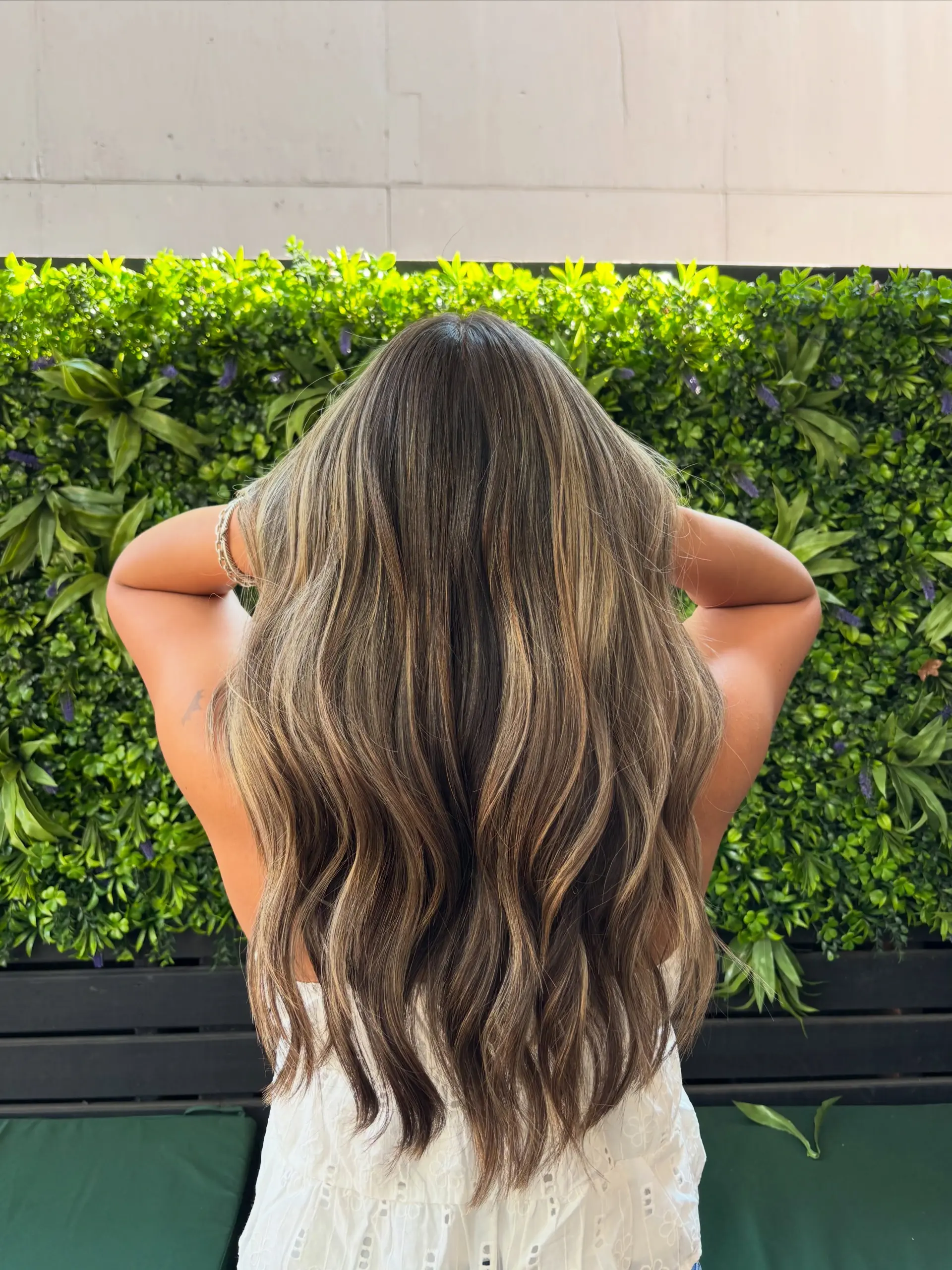 Long cascading waves featuring a dimensional blend of rich brunette lowlights and caramel-blonde highlights. 1