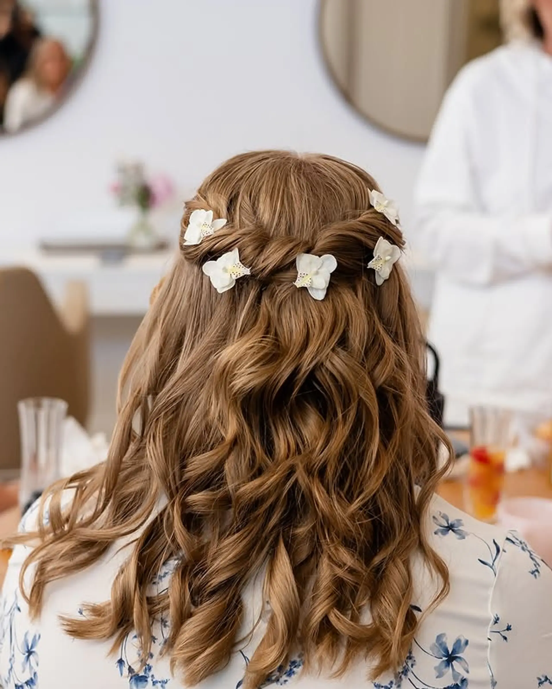 A braided half-updo with wavy texture and delicate floral accents. 1
