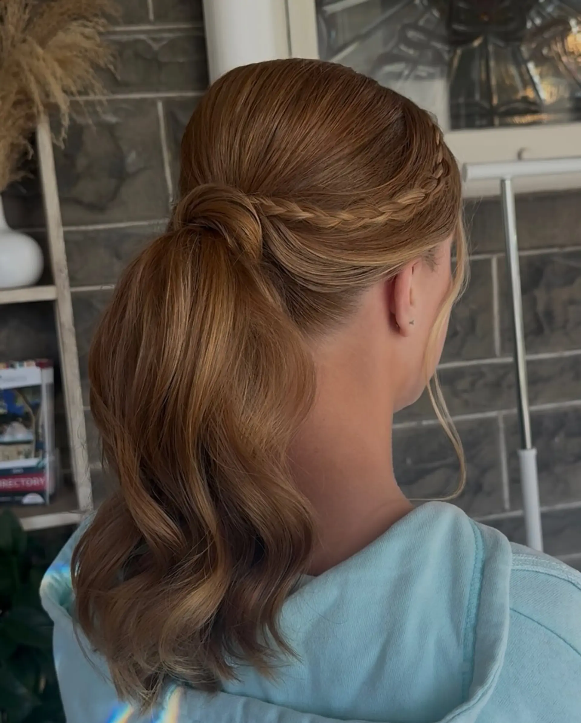 A sleek, formal ponytail featuring a delicate side braid woven into a hair-wrapped base with soft, wavy ends. 1