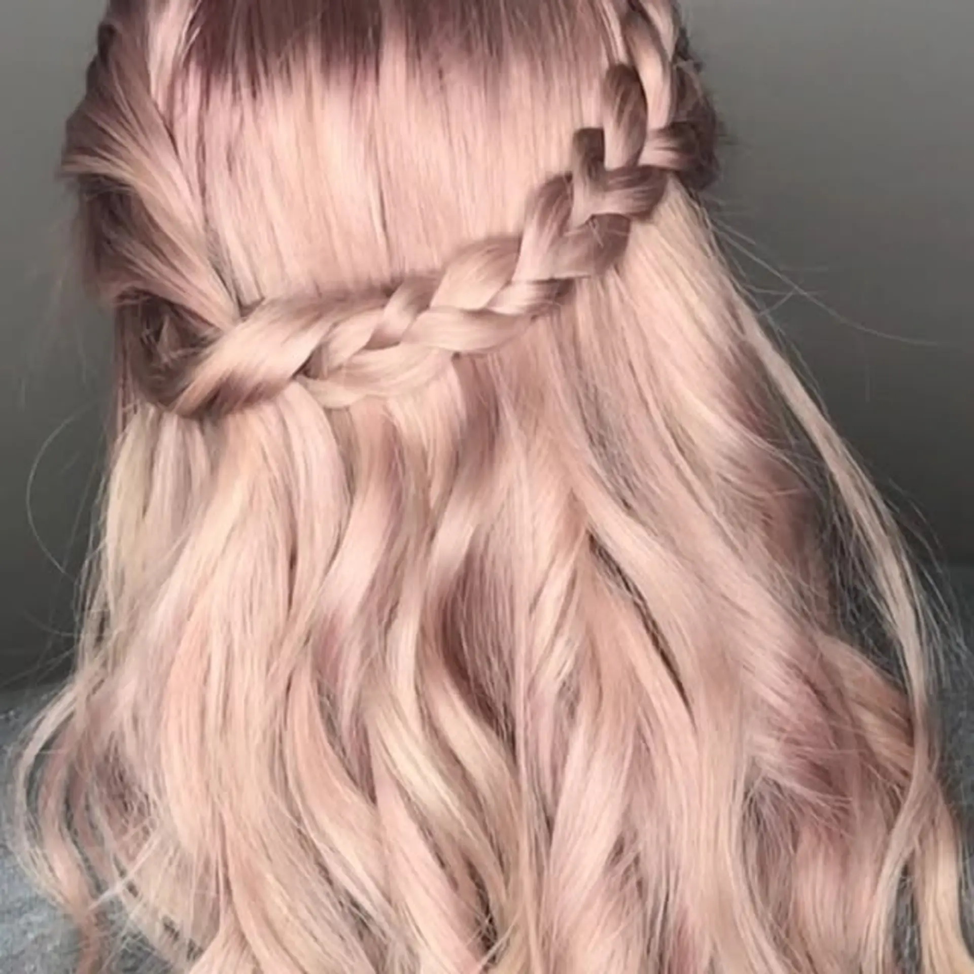 Long iridescent titanium rose hair styled in soft waves with a braided half-up crown accent across the back. 1