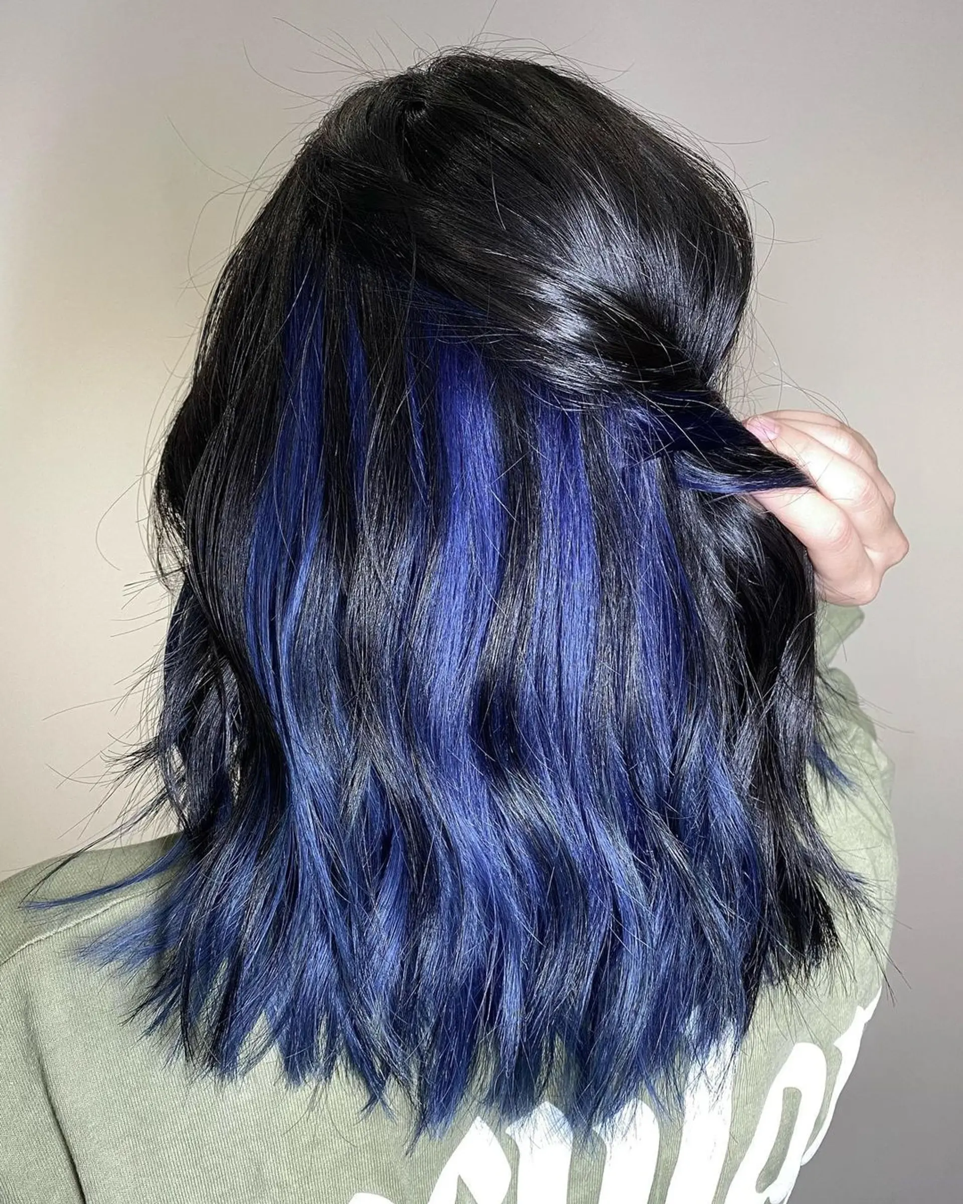 Medium-length wavy hair with black base and blue balayage highlights cascading in textured layers for a lived-in, glamorous look. 1