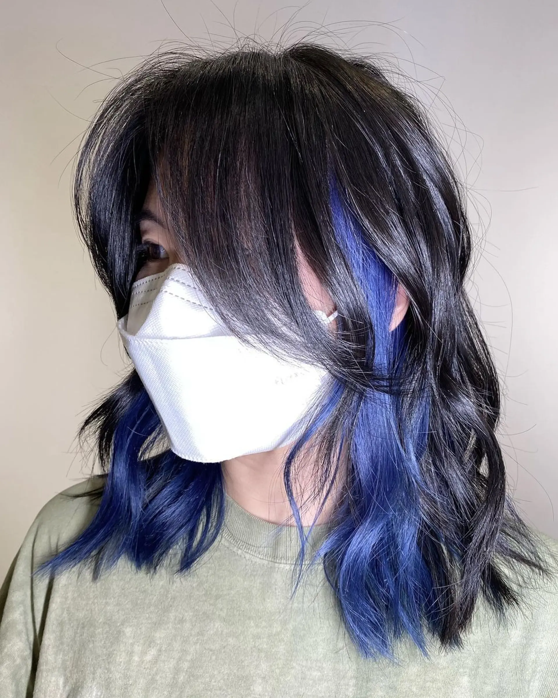 Medium-length wavy hair with black base and blue balayage highlights cascading in textured layers for a lived-in, glamorous look. 2