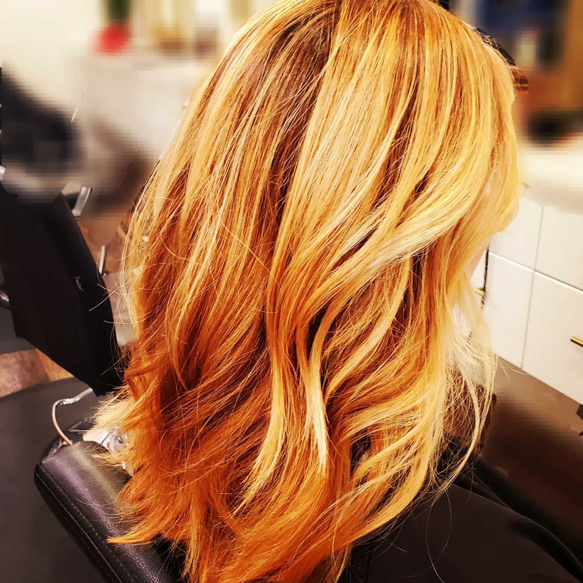 Vibrant strawberry blonde hair featuring dimensional warm highlights, styled into soft, layered waves. 1