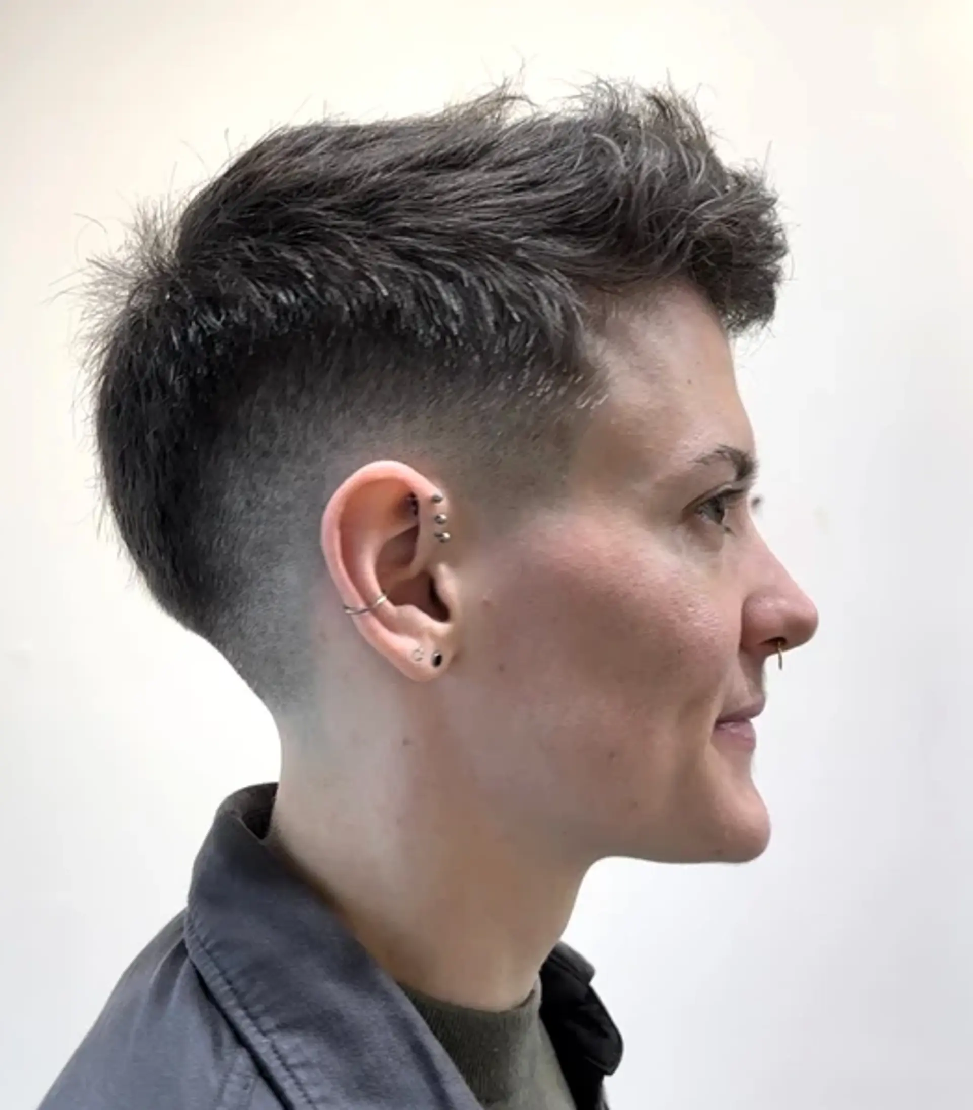 Short, wavy textured top with an undercut and taper fade, styled with a side sweep. 1
