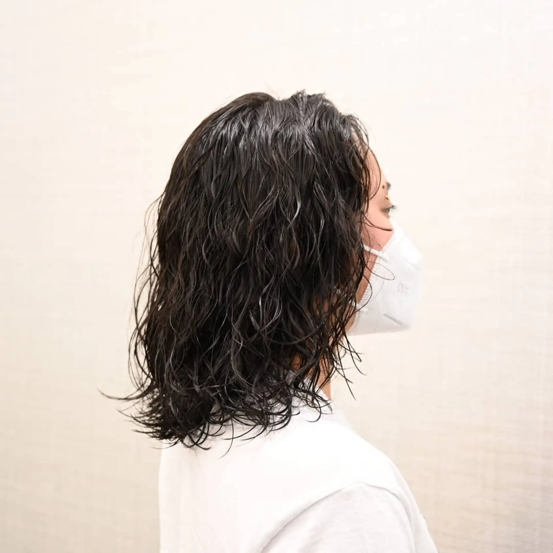 A textured shoulder-length haircut styled with damp, defined permed waves and wet-look definition. 1