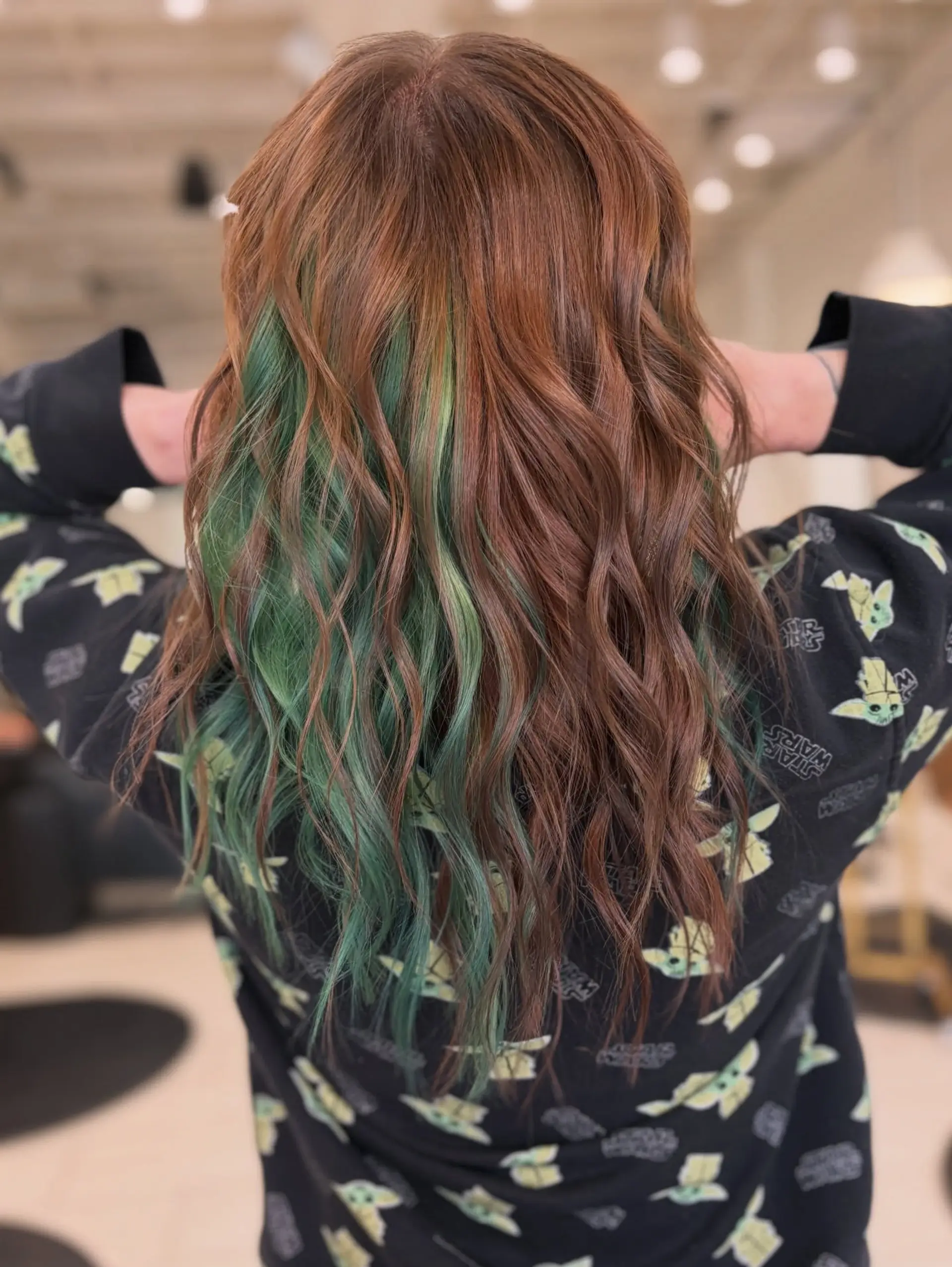 Medium-length wavy auburn hair featuring a hidden vibrant green peekaboo underlayer exposed through soft, textured waves. 1