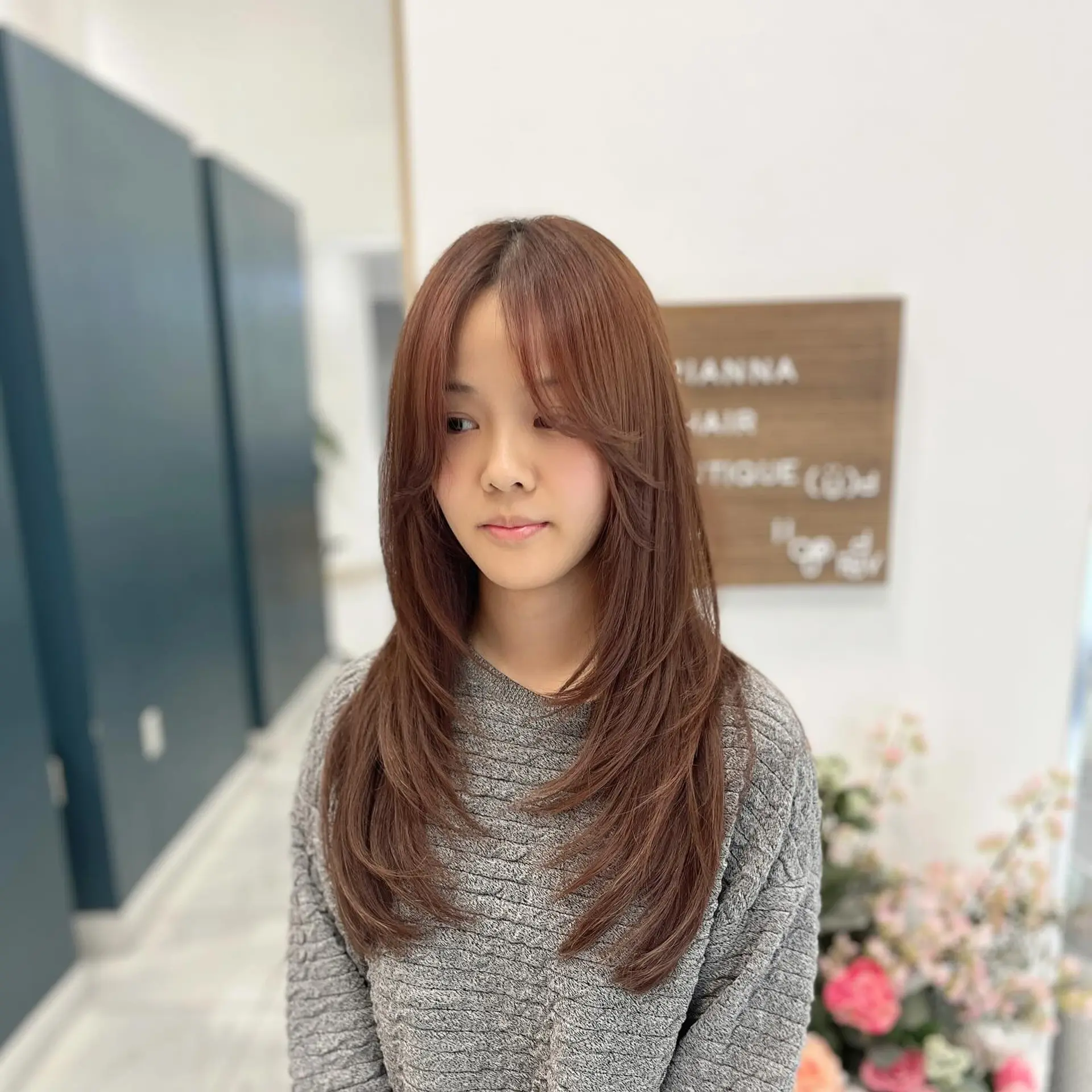 Long chestnut brown layered haircut with soft curtain bangs and feathered face-framing layers styled with curved ends. 1