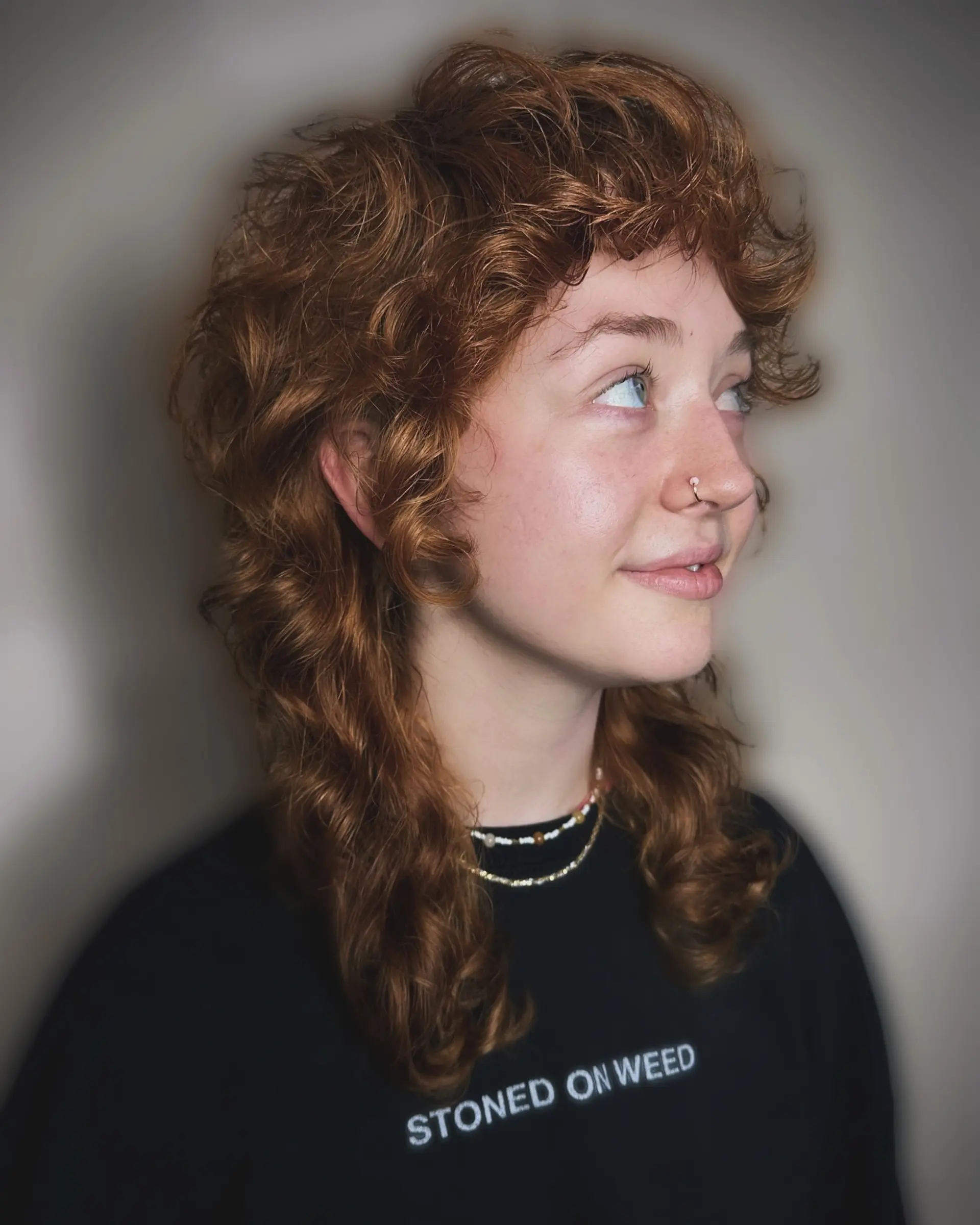 A textured curly shullet haircut featuring soft curly fringe bangs and voluminous layers flowing into longer shoulder-length curls. 1