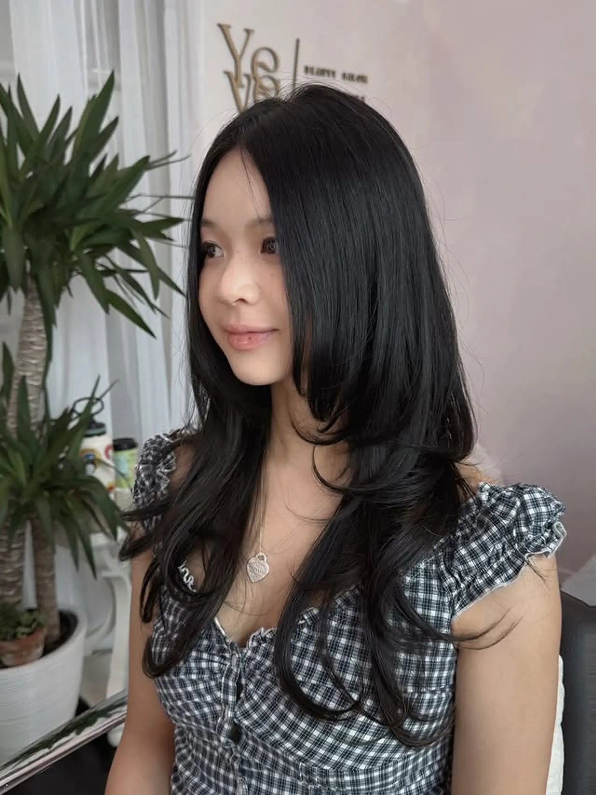 A chic long layered haircut with significant face-framing pieces that softly contour the face. This style emphasizes volume and movement, with a smooth top section flowing into gentle waves at the mid-lengths and ends. 1