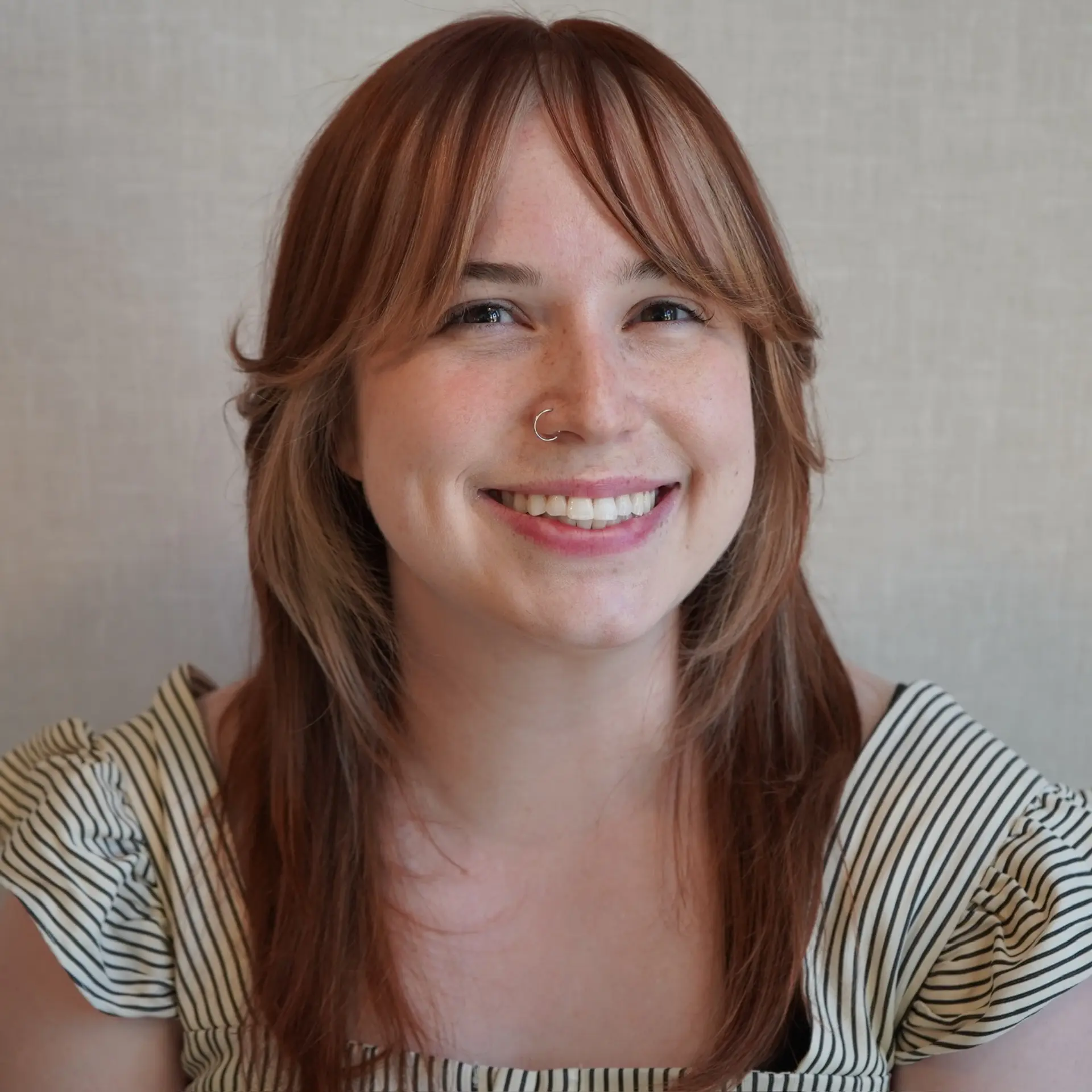 Medium-length haircut featuring feathered, cheekbone-skimming curtain bangs and soft, face-framing layers that curve gently inward. 1