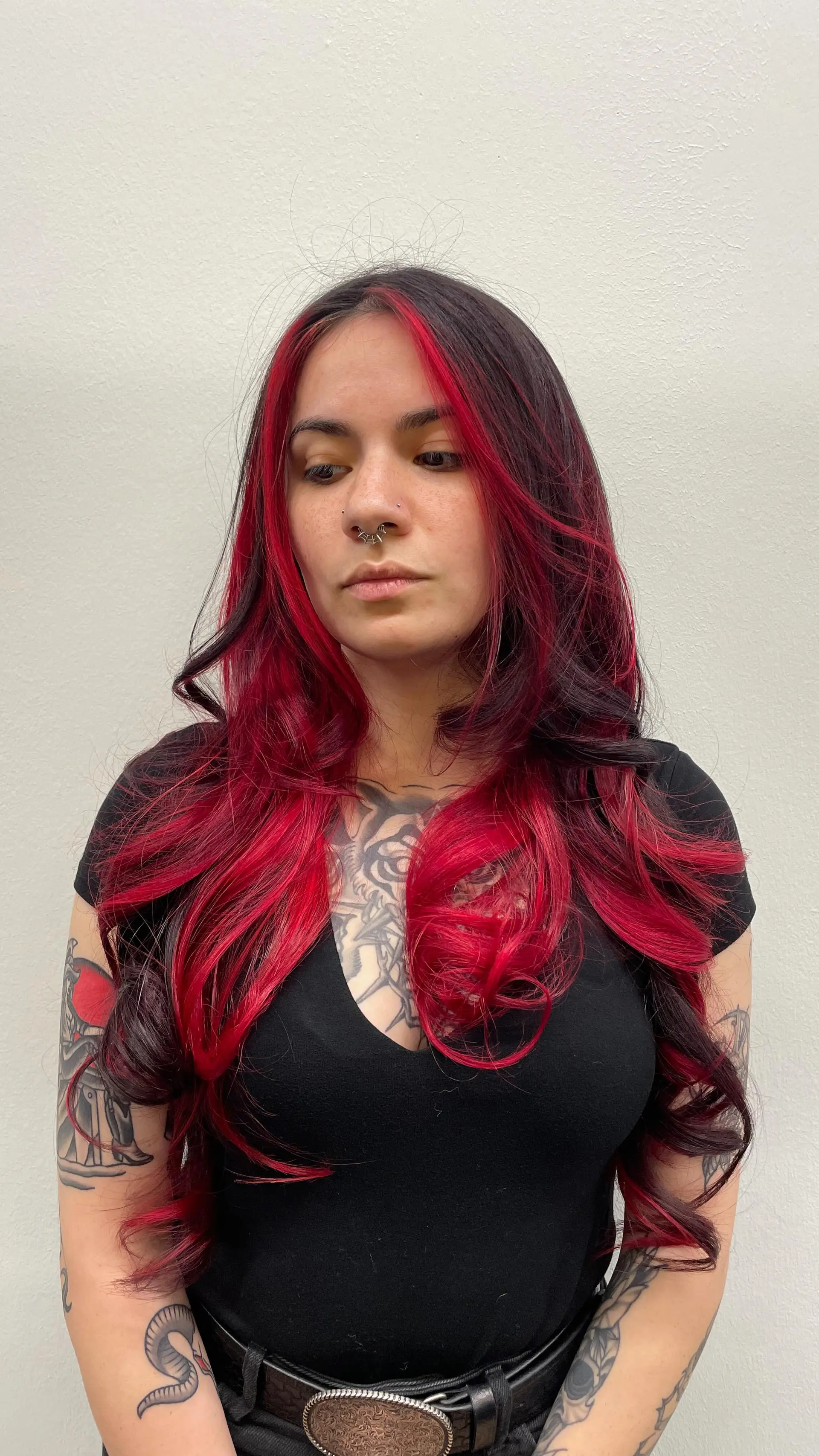 Long dark wavy hair styled with bright cherry red face-framing money pieces and red dimensional streaks. 1