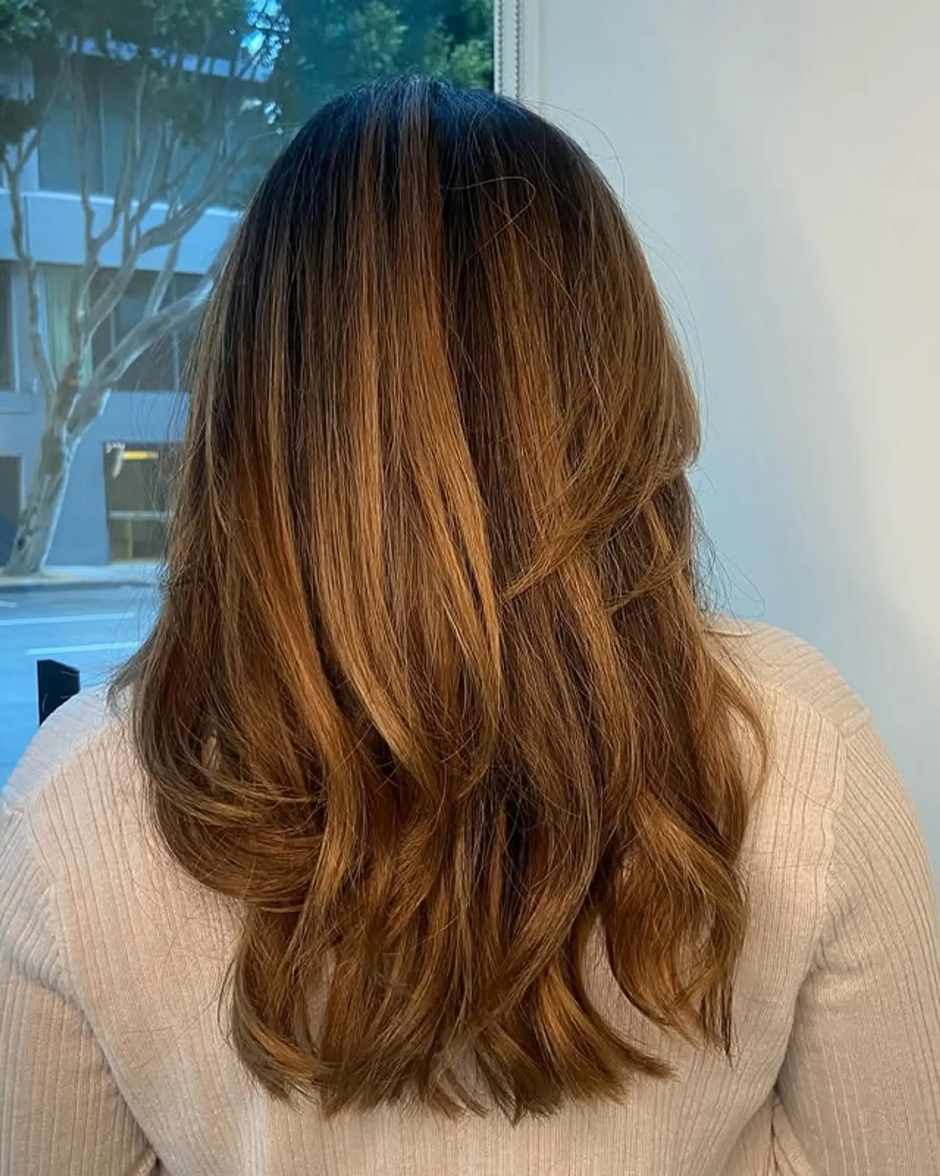 A layered long hairstyle with a bronde color melt and soft waves. 1