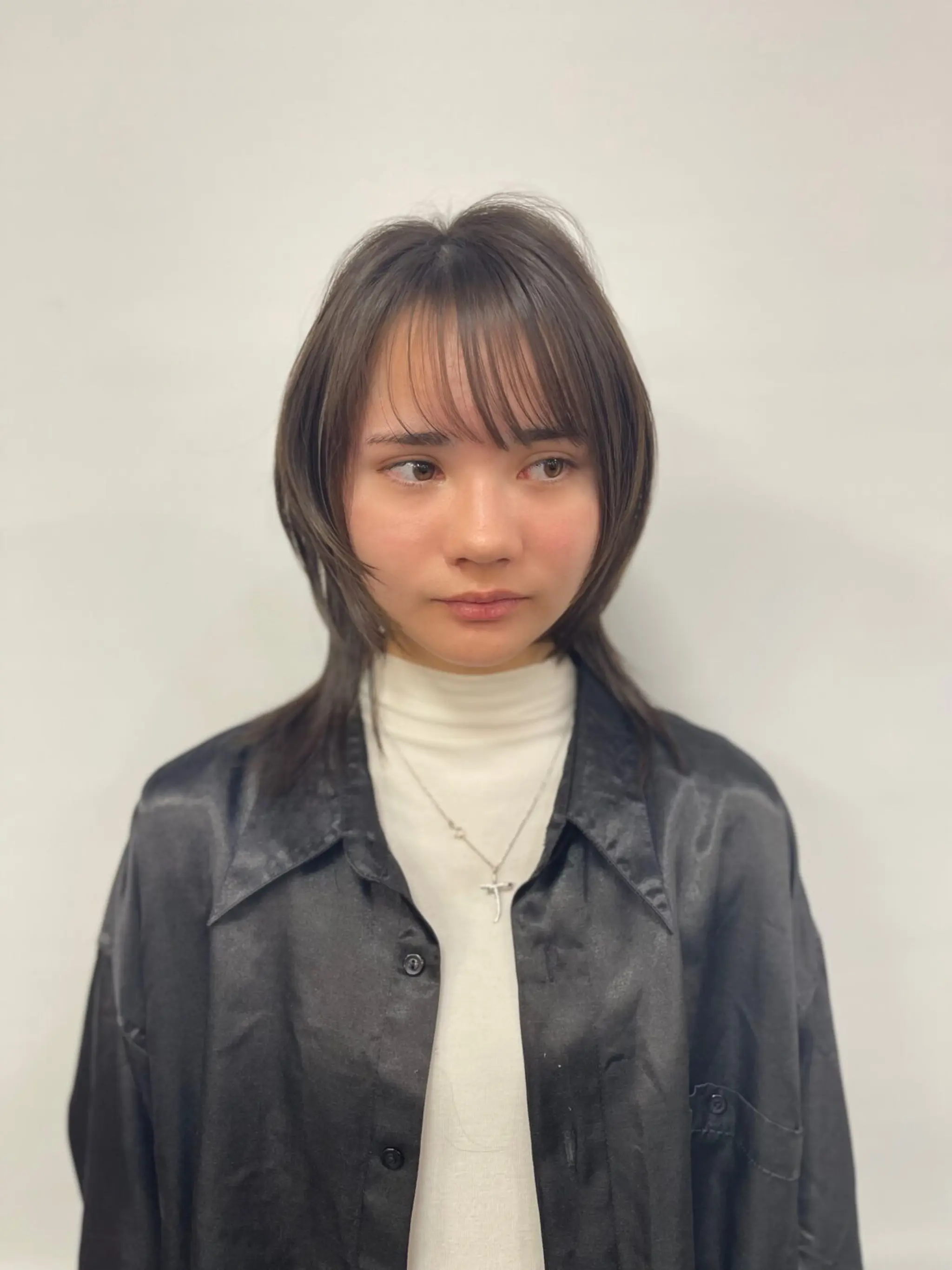 Medium-length dark brown hair with elegant layers, face-framing bangs, and a smooth, shiny finish.
