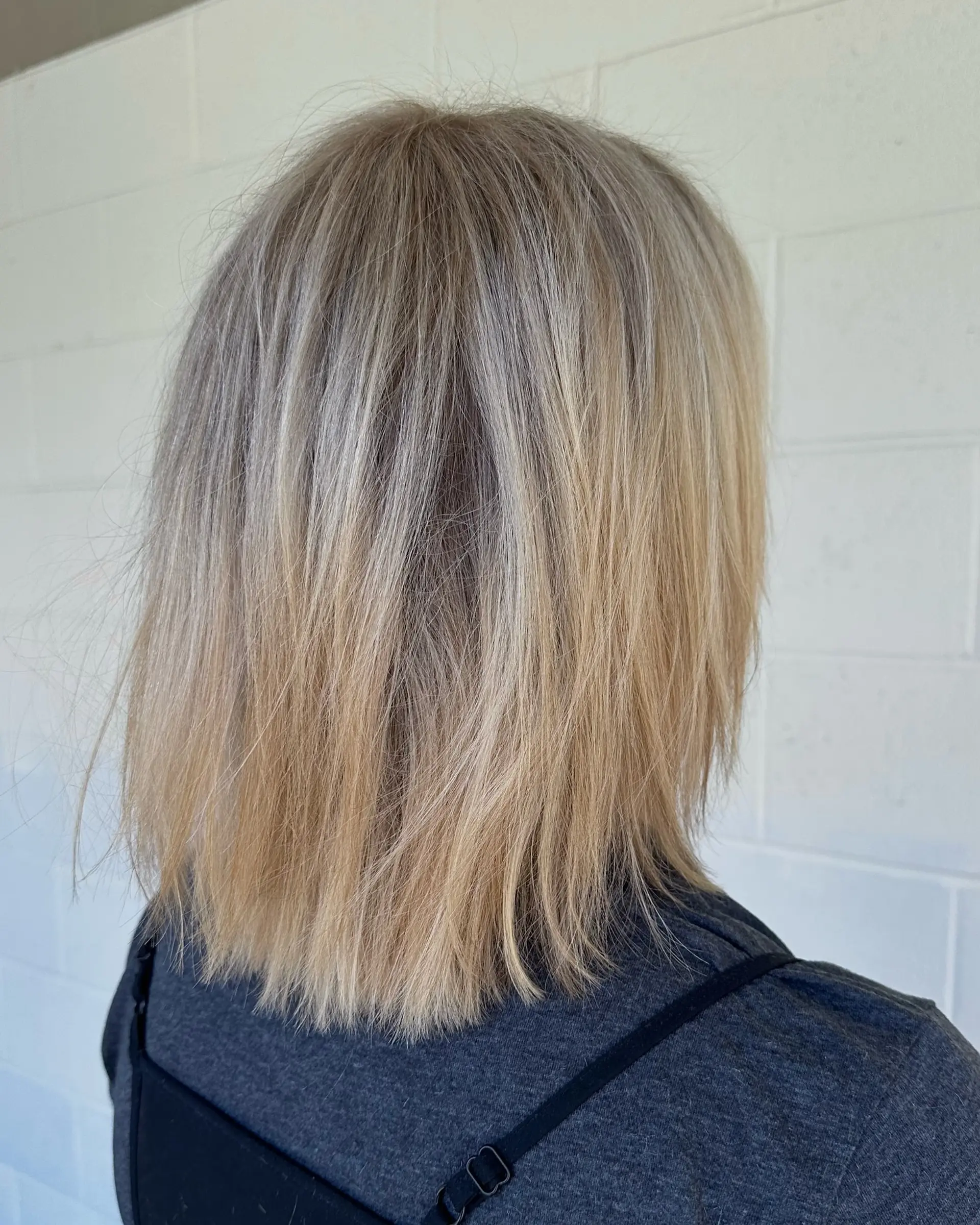 A textured, collarbone-grazing blonde bob cut styled straight with soft, wispy ends and multi-tonal highlights. 1