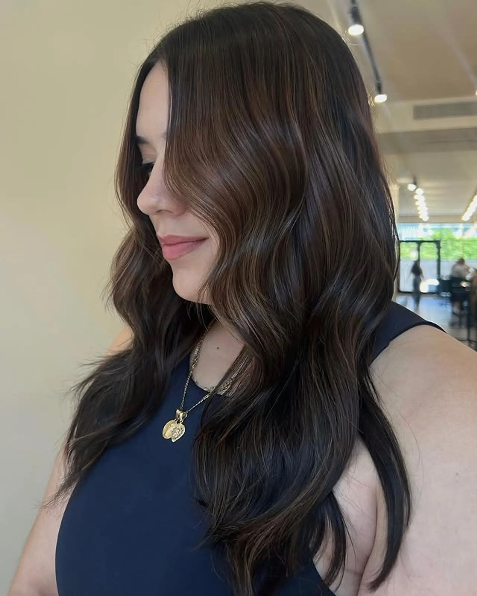 Medium length wavy hair with a balayage that blends chocolate brown with subtle blonde highlights. 1