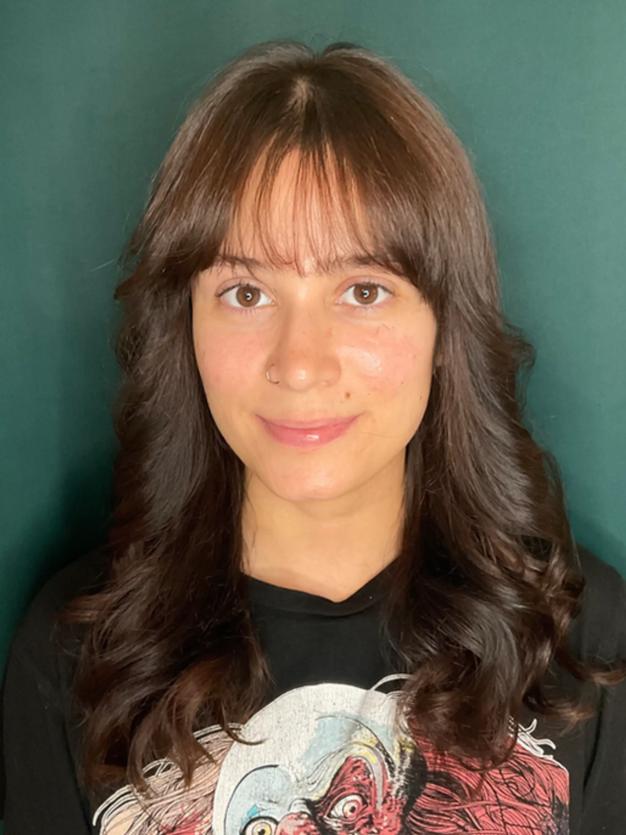 Long brown hair styled with wavy layers and a fringe, showcasing a glossy finish.