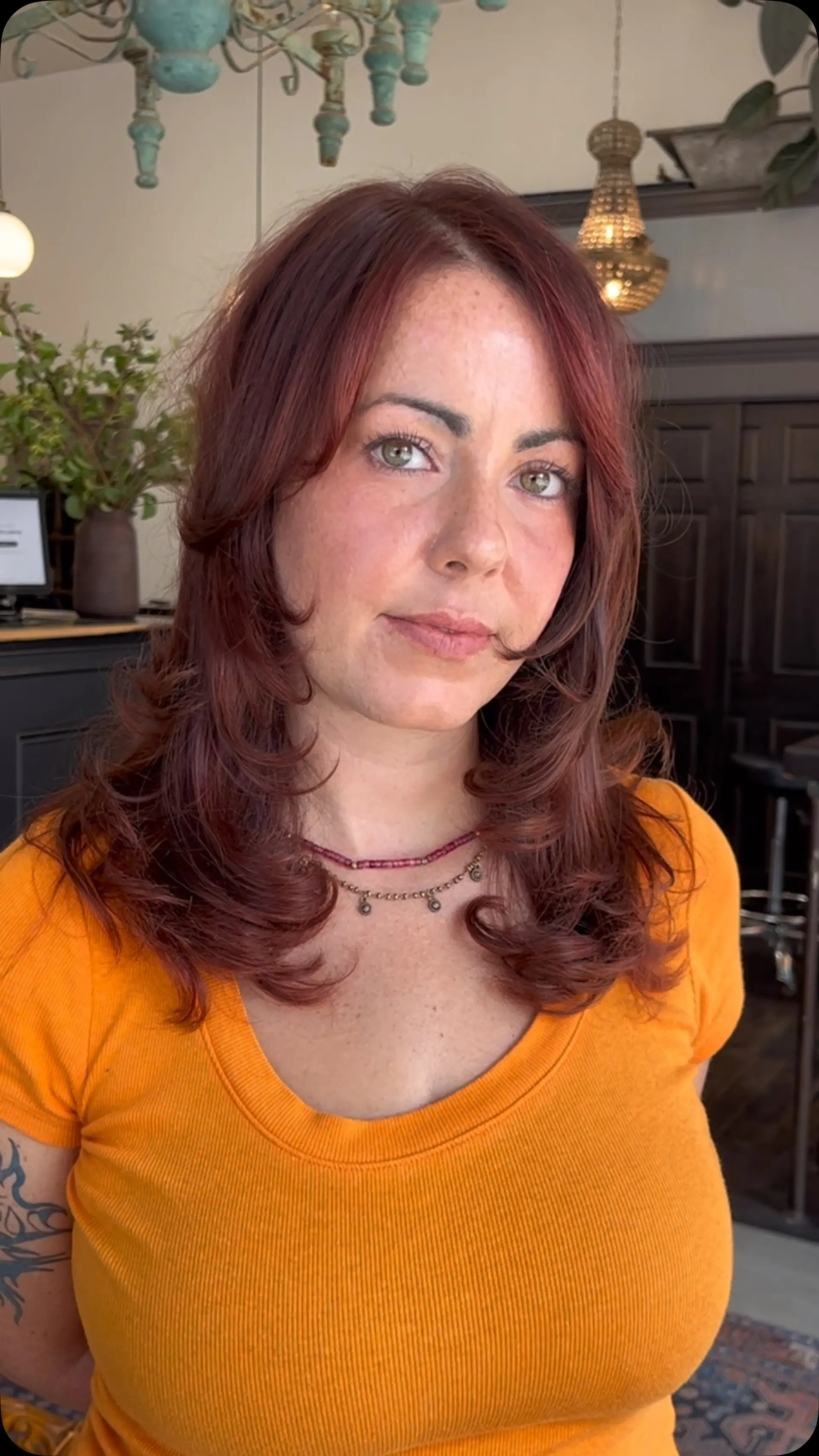 Medium-length rich auburn hair cut with heavy textured layers and face-framing bangs styled with bouncy, rounded ends. 1