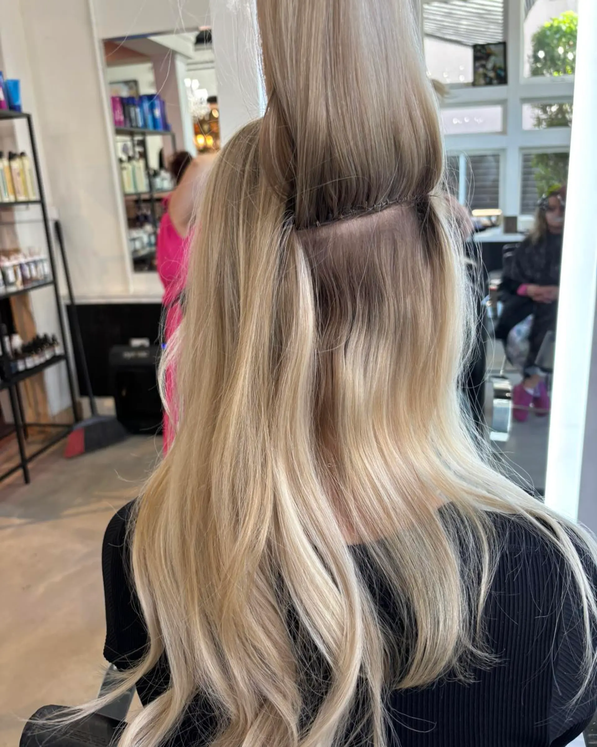 A clean hand-tied weft extension installation blended into long, dimensional blonde hair. 1