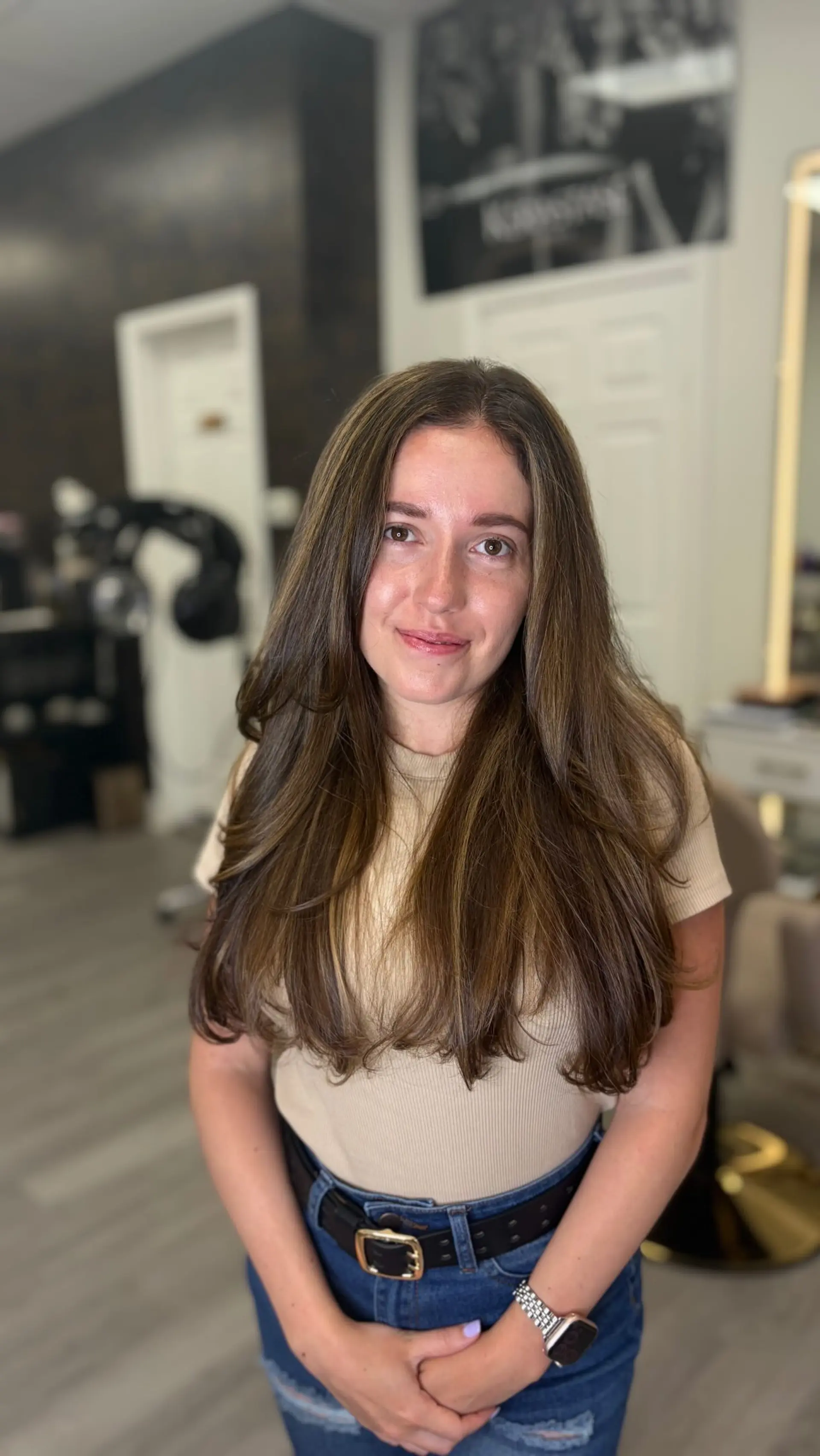 Long layered brunette hair with delicate highlights, styled into a smooth, voluminous blowout with softly curled ends. 1