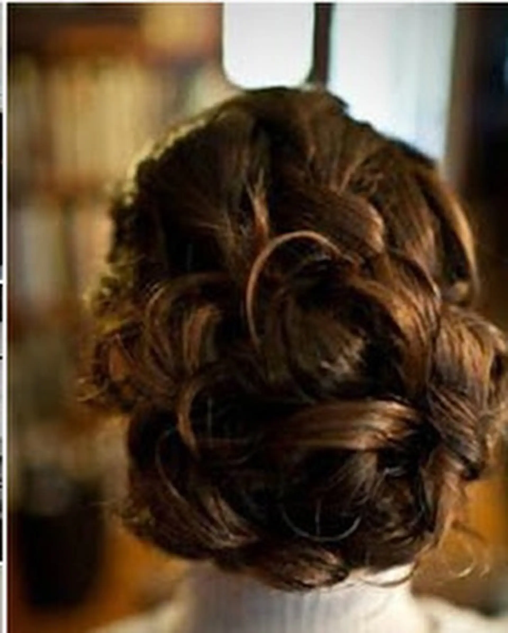 A formal updo featuring pinned curls and twists arranged into an elegant textured bun at the back of the head. 1