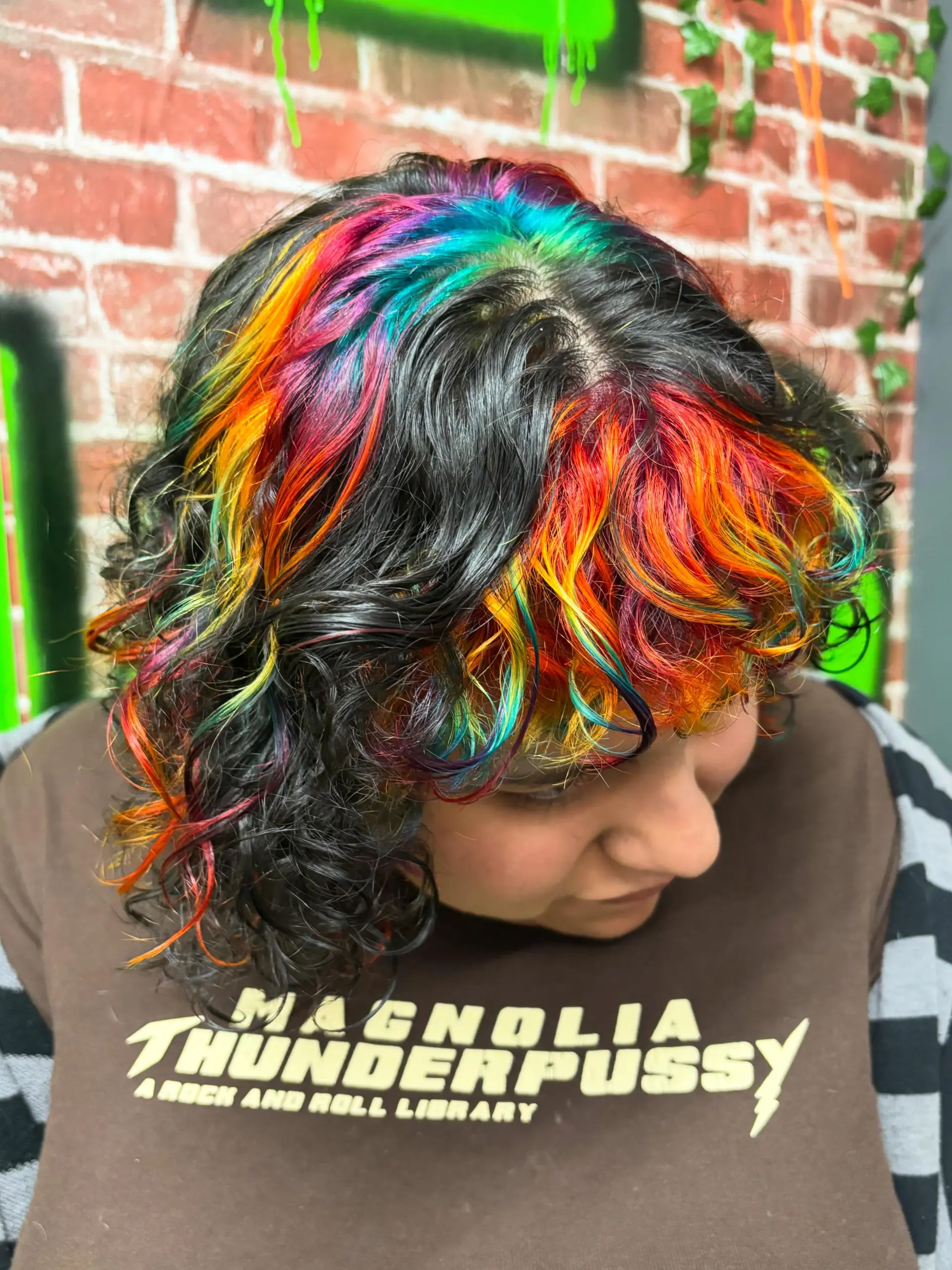 Short curly dark hair highlighted with vibrant rainbow vivid color panels across the crown and fringe. 1