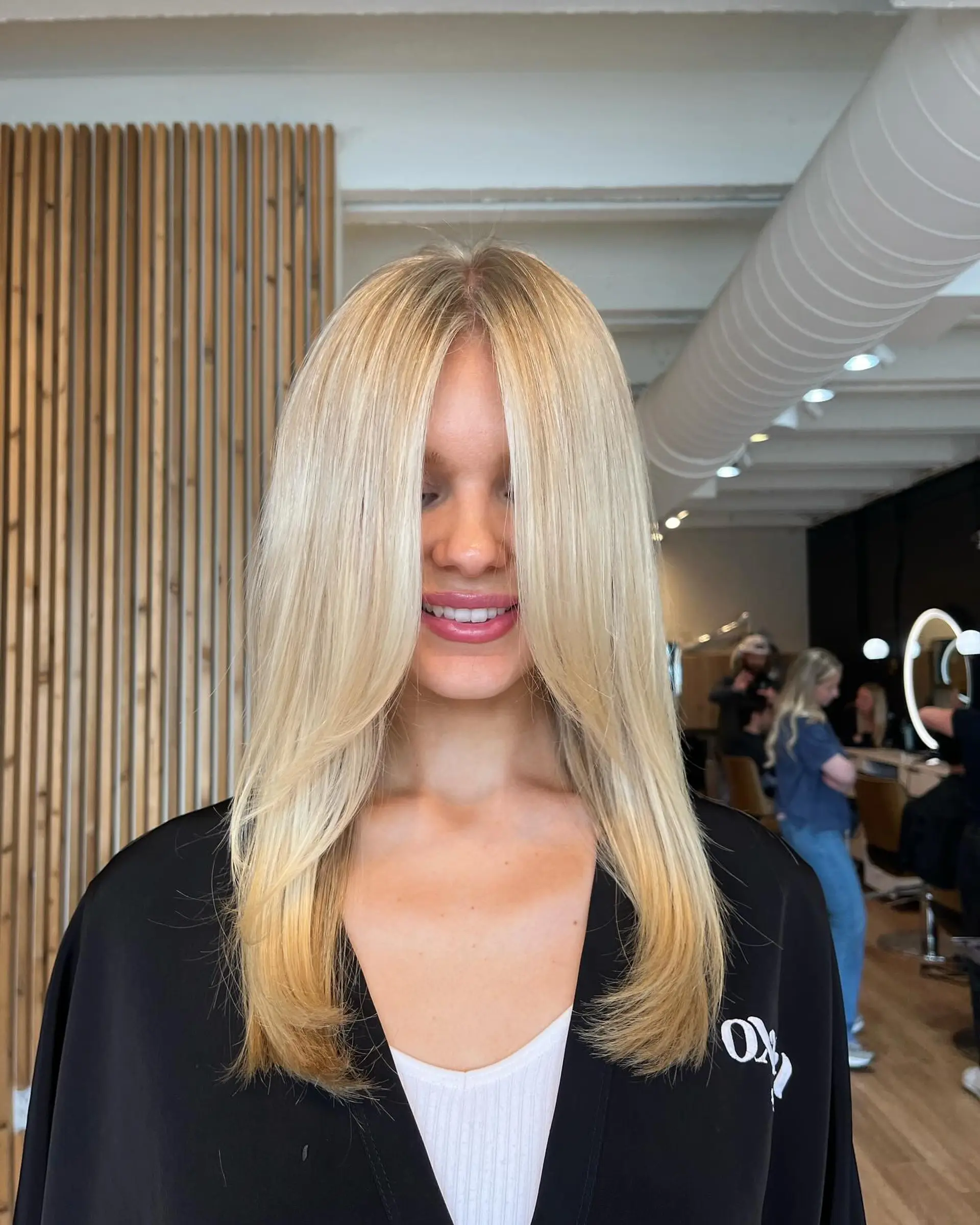 Long, bright blonde hair styled straight with a center part and smooth face-framing layers. 1