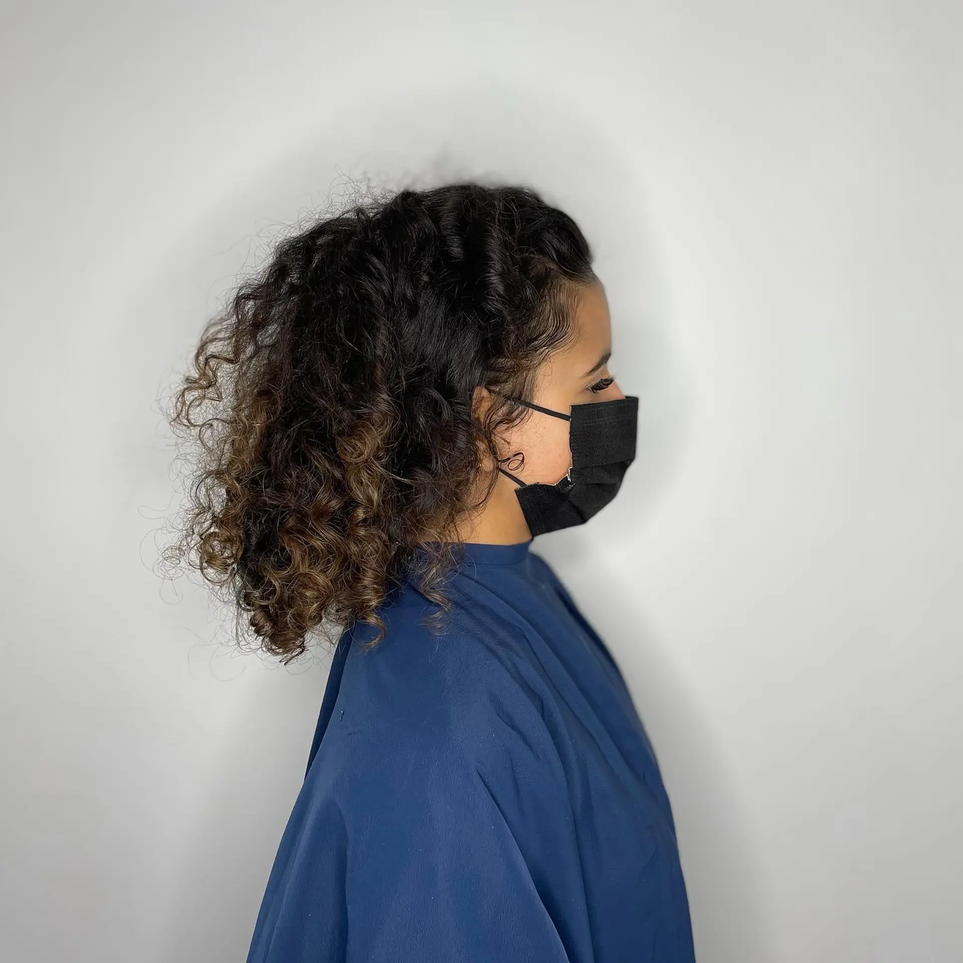 A voluminous, shoulder-grazing layered cut styled with natural defined curls and subtle warm brown highlights towards the ends. 1