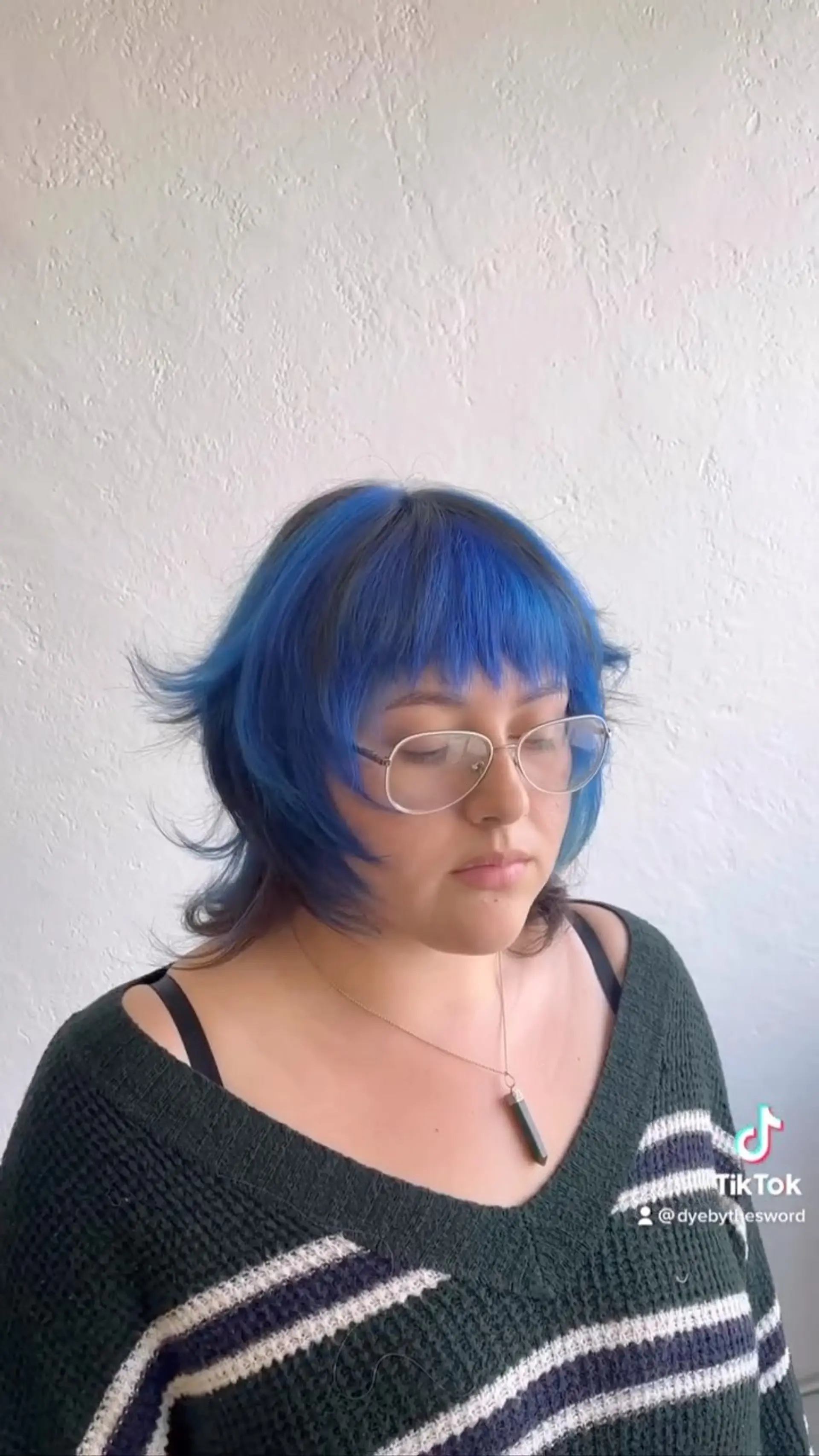A textured layered shag with vivid electric blue color over dark roots, featuring full fringe bangs and flicked ends. 1