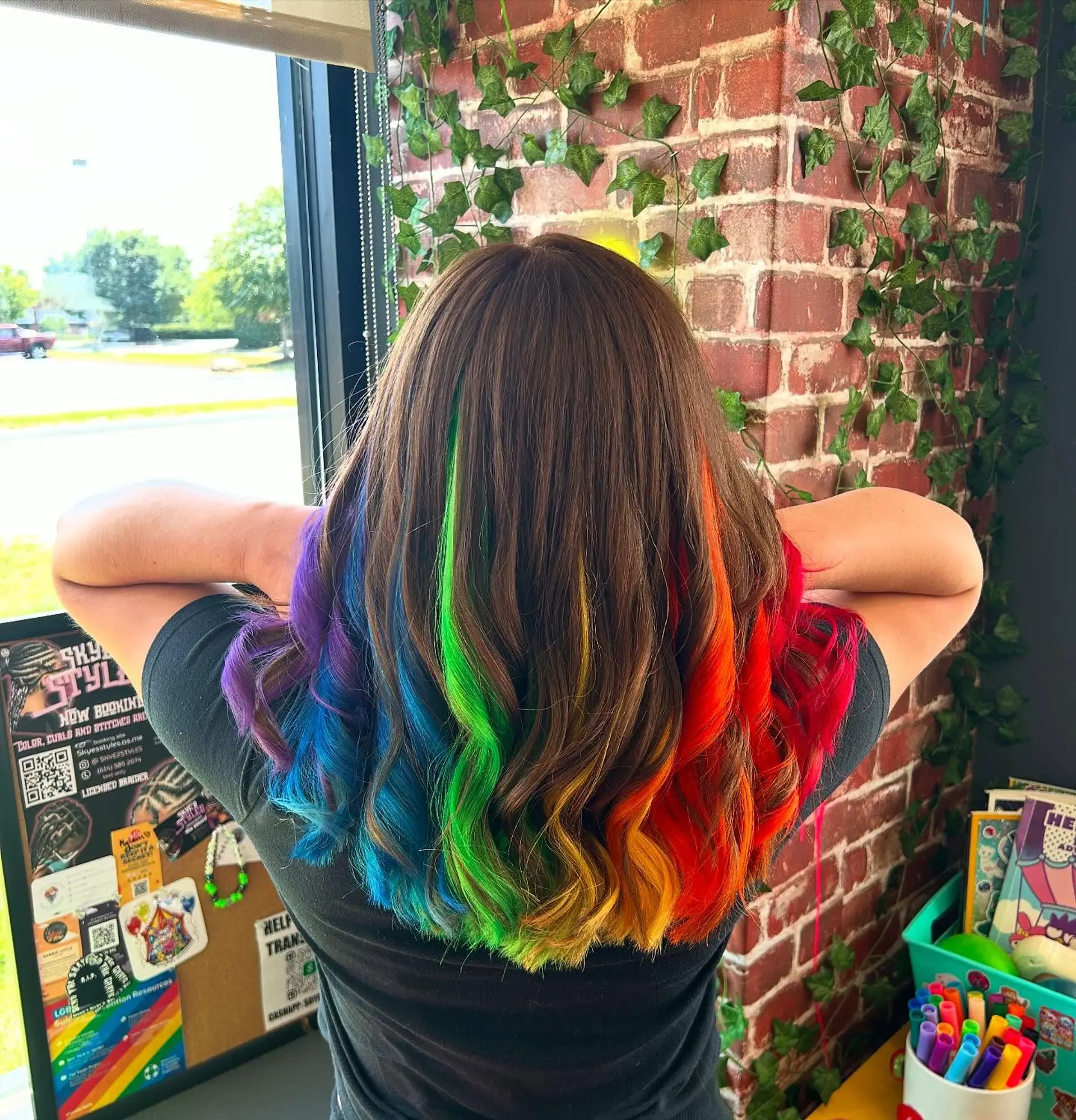 Medium-length brunette hair styled in loose waves, revealing a vibrant hidden rainbow underlayer beneath. 1