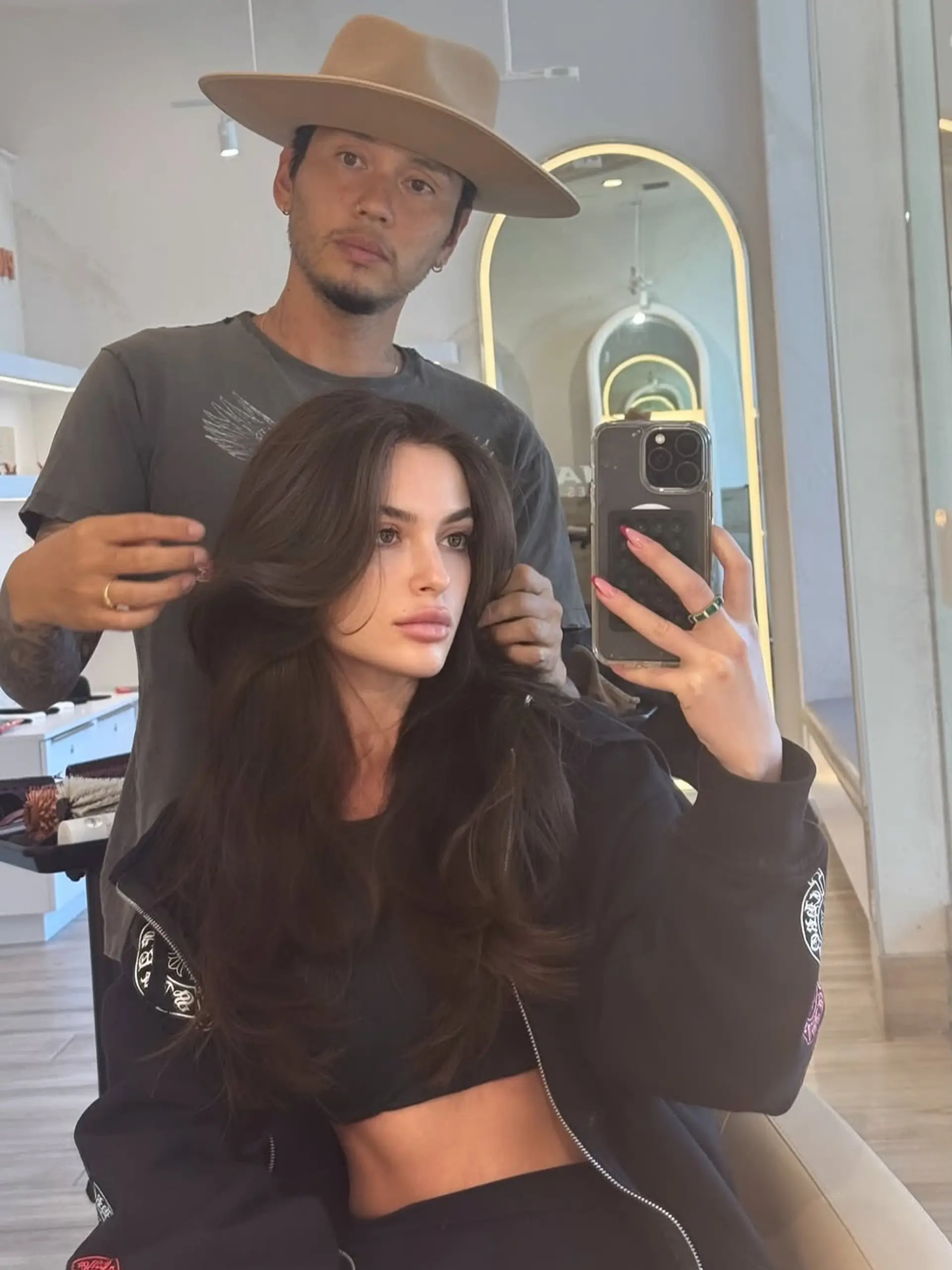 Long dark brunette hair featuring face-framing curtain bangs and voluminous butterfly layers styled in soft waves. 1