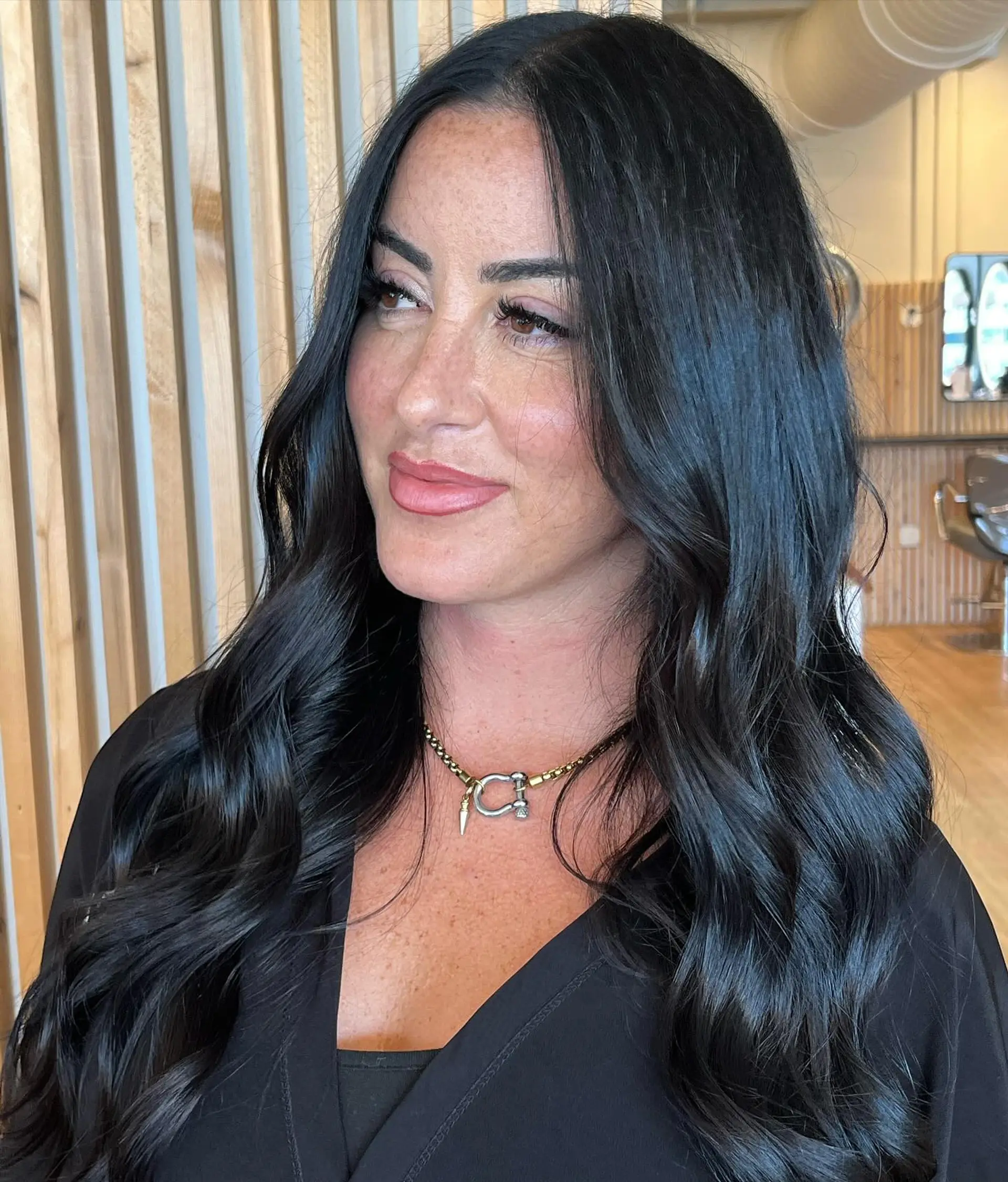 Long, radiant midnight black hair styled with loose, polished waves and a clean center part. 1