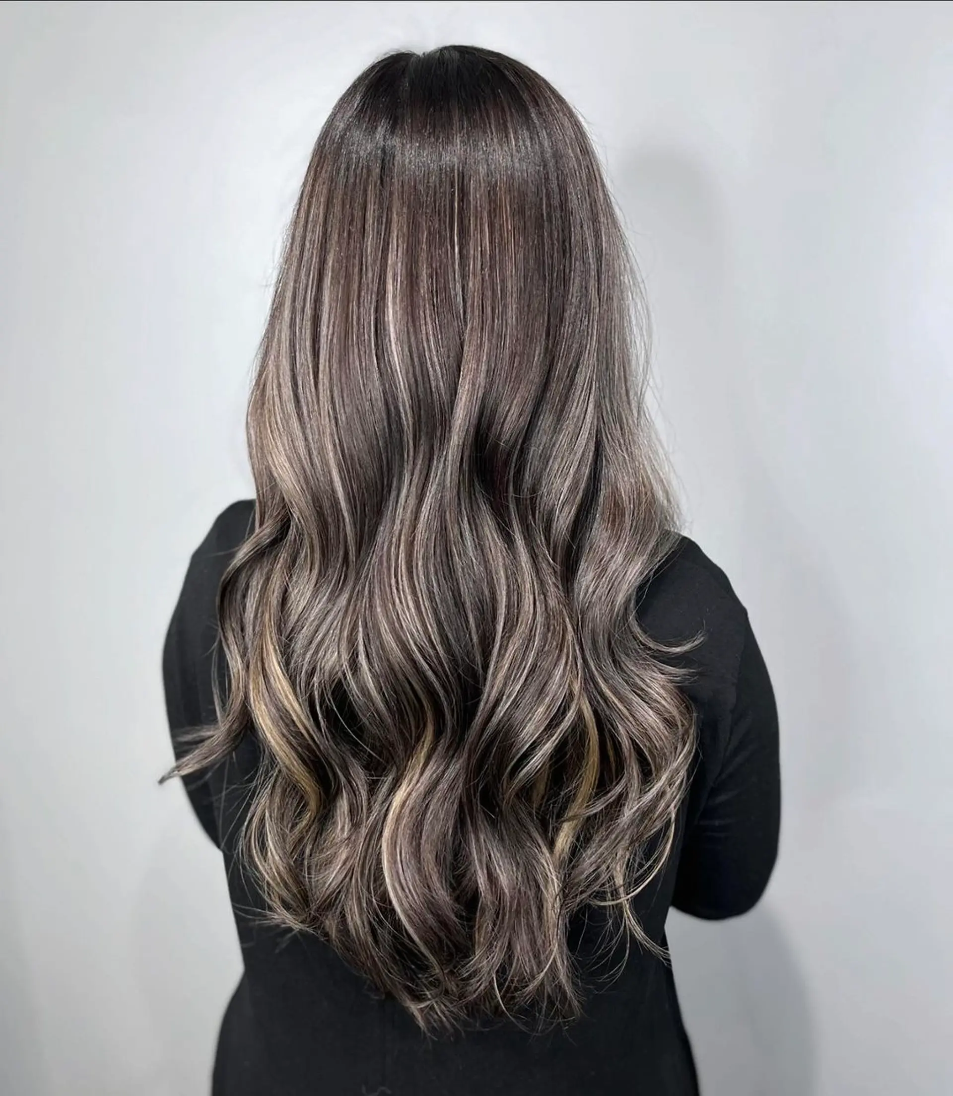Long wavy hairstyle with a natural dark brown base, ash brown balayage, and silver highlights providing a multidimensional effect. Soft waves add movement and texture, and the glossy finish gives a sleek, healthy appearance.
Stylist - @xcellent_jason 1