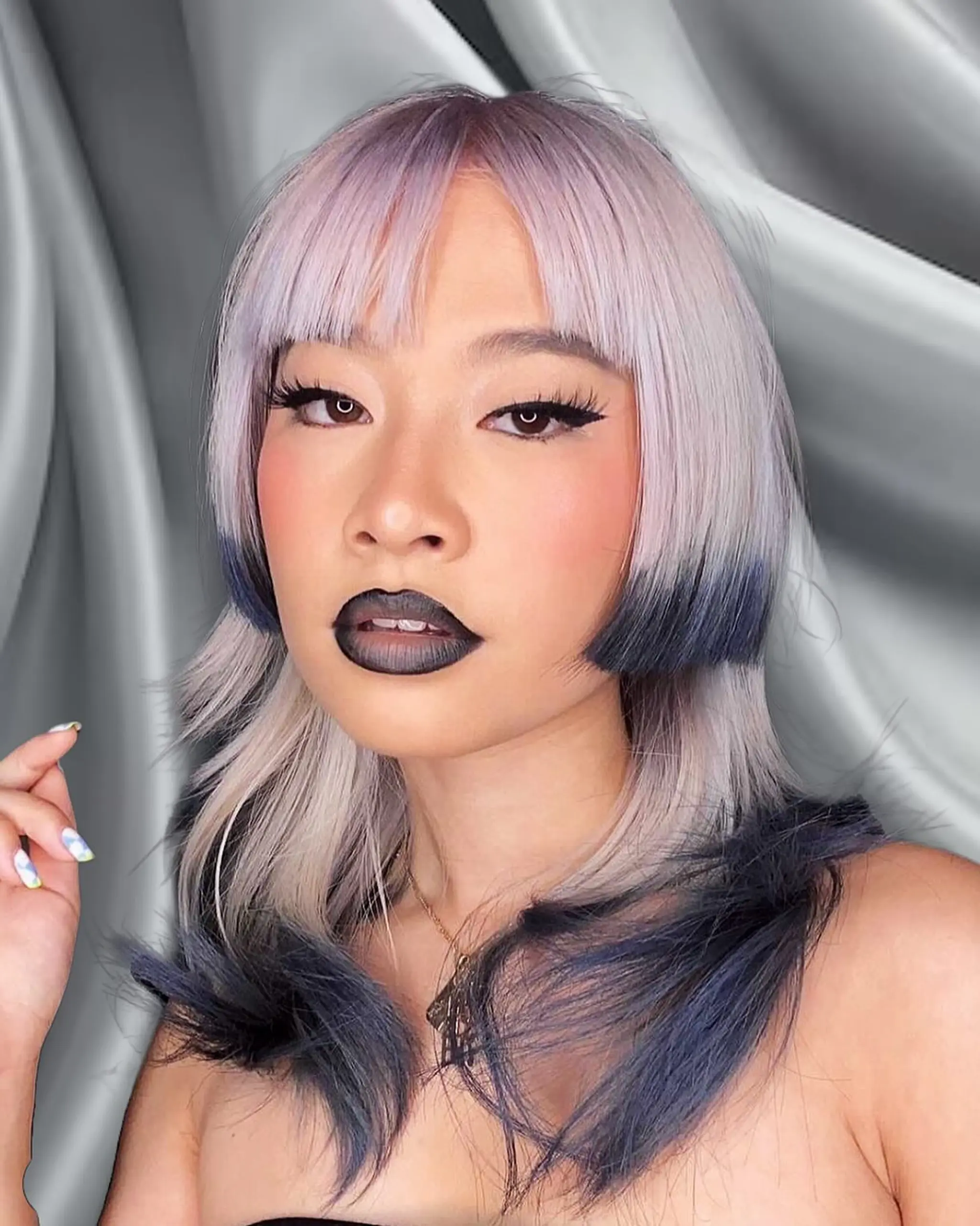 A medium-length straight hairstyle with platinum blond base and dark blue tips, featuring full fringe bangs and layers for a modern, edgy look.