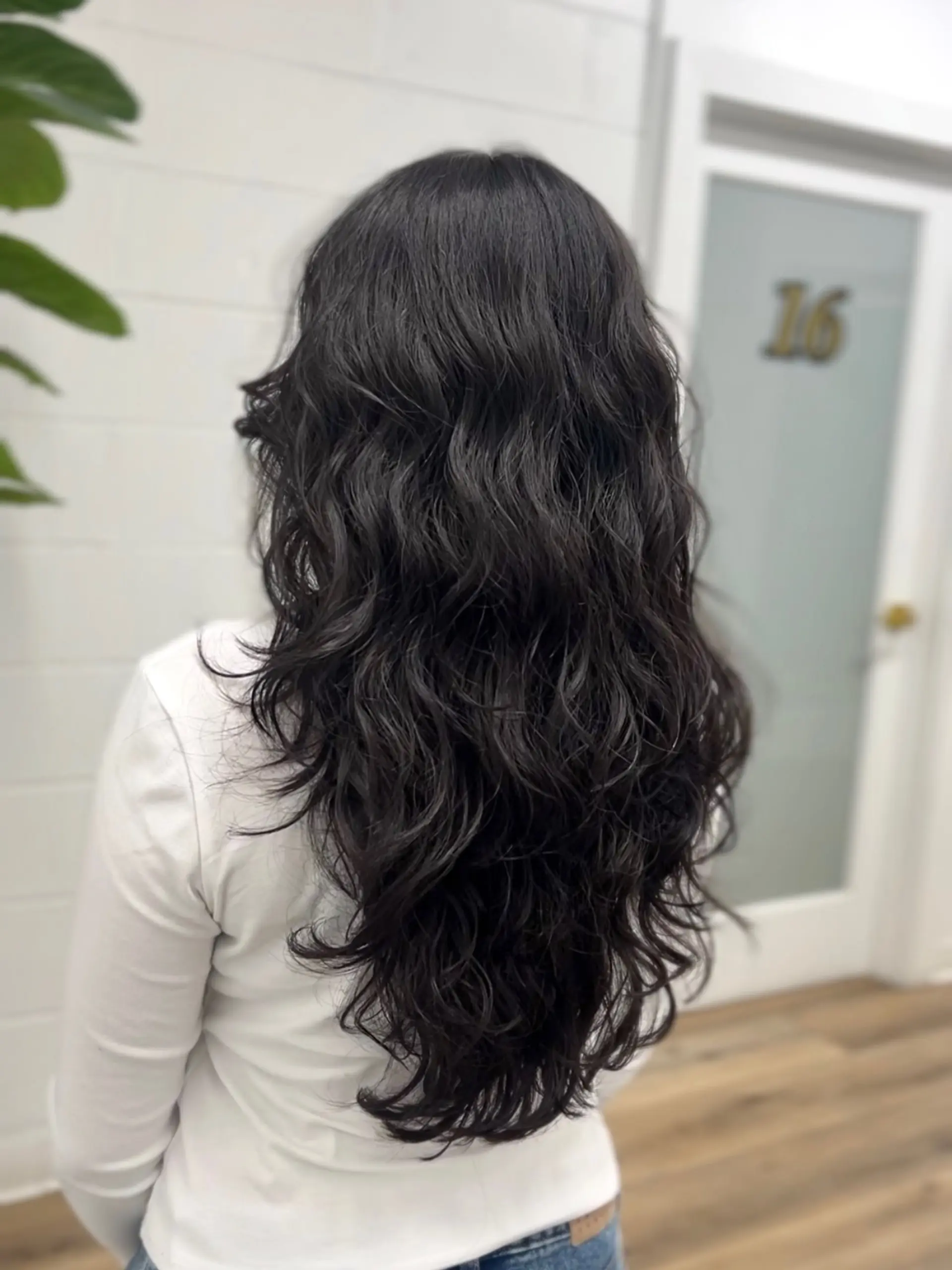 Long, layered black hair styled into soft, voluminous waves created with a digital perm. 1