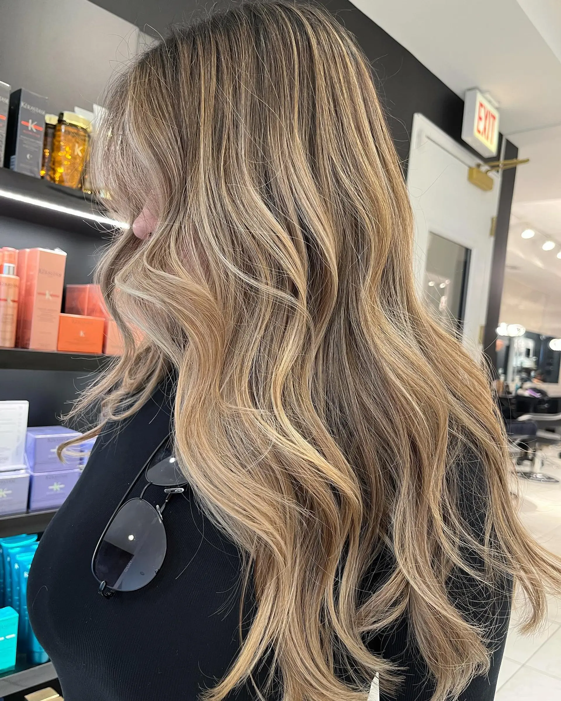 Long wavy hair with a seamless blend of blonde and brown tones, styled into effortless beachy waves. 1