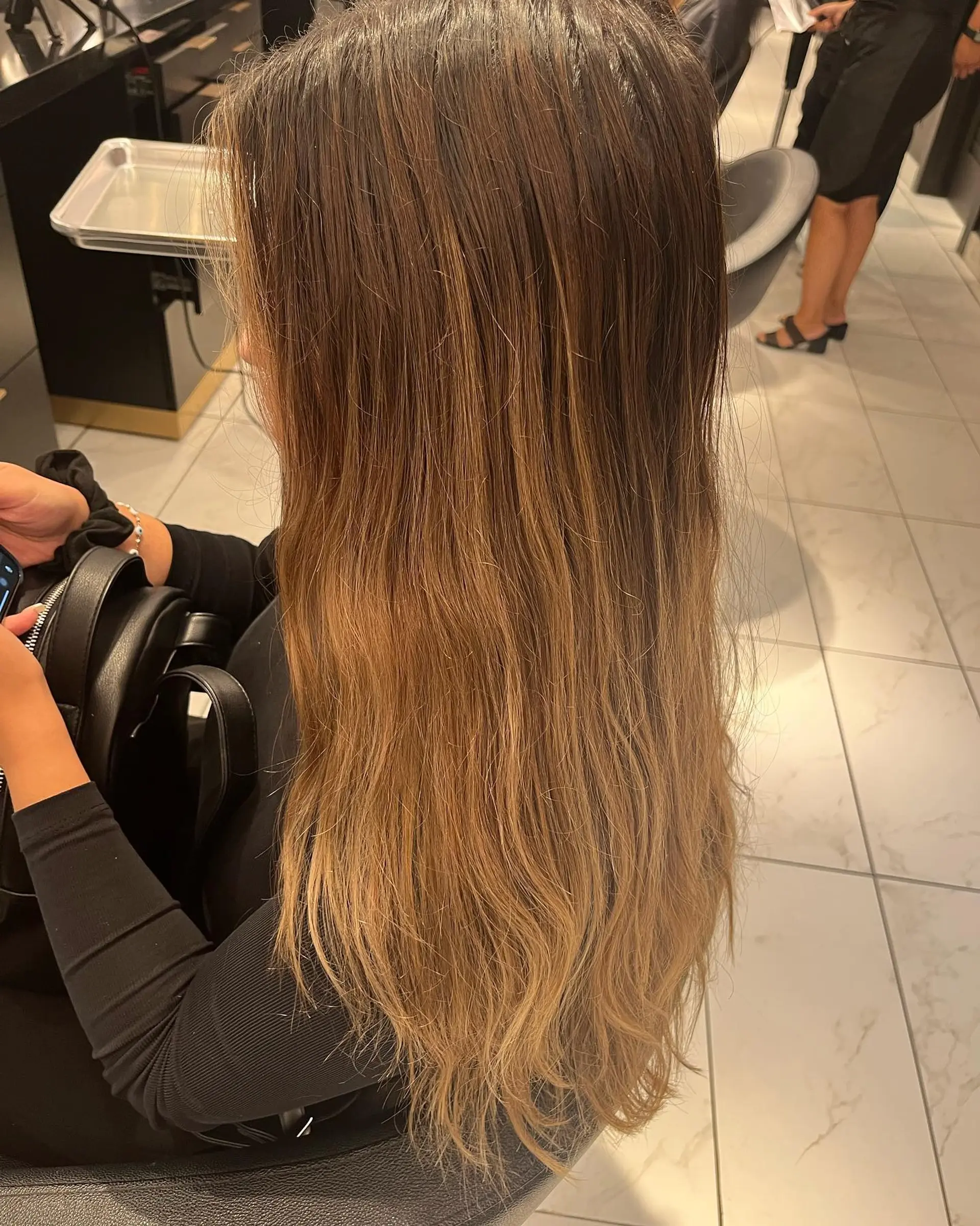 Long wavy hair with a seamless blend of blonde and brown tones, styled into effortless beachy waves. 2