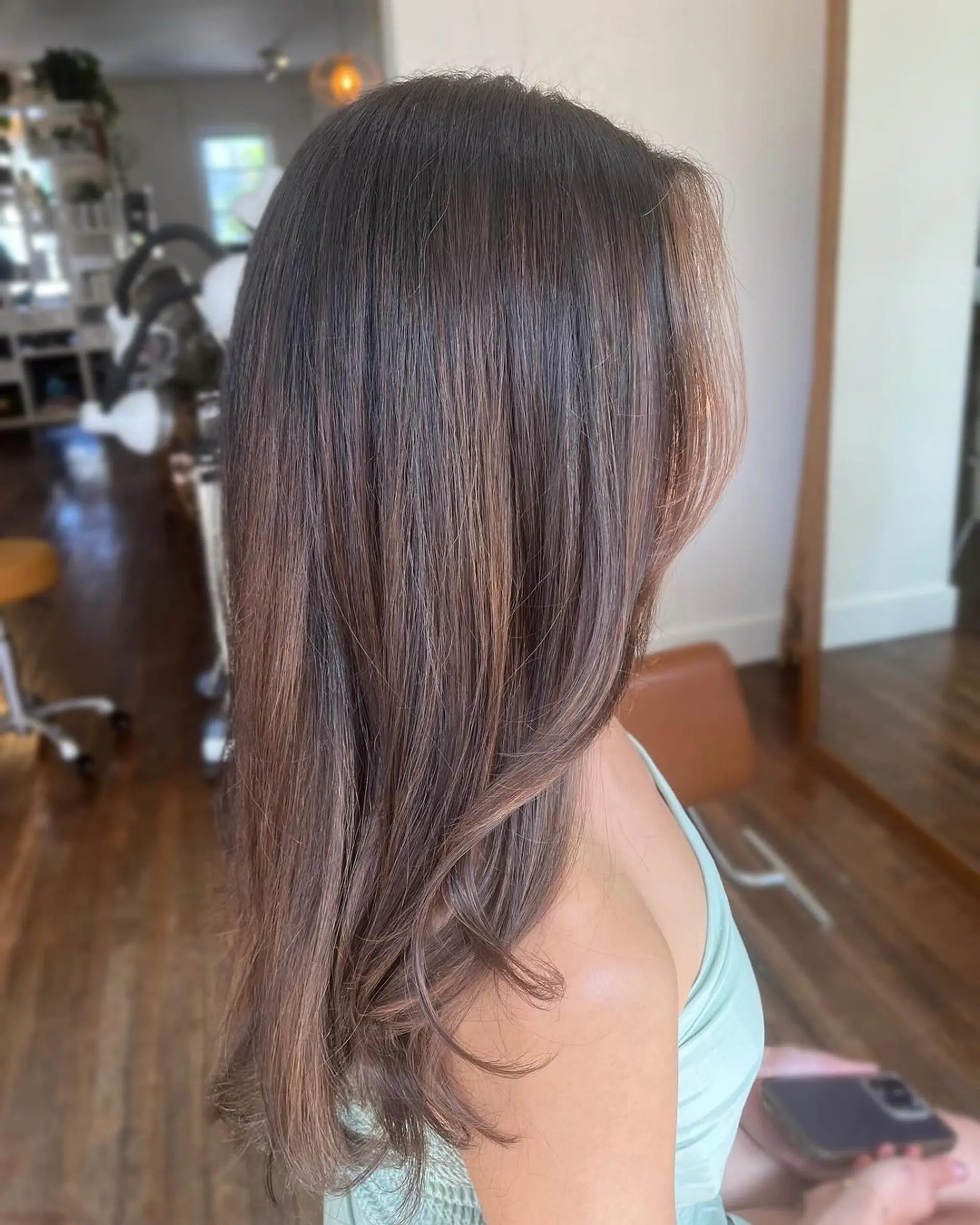 Long, wavy brown hair with soft, honey blonde highlights and a natural part. 1