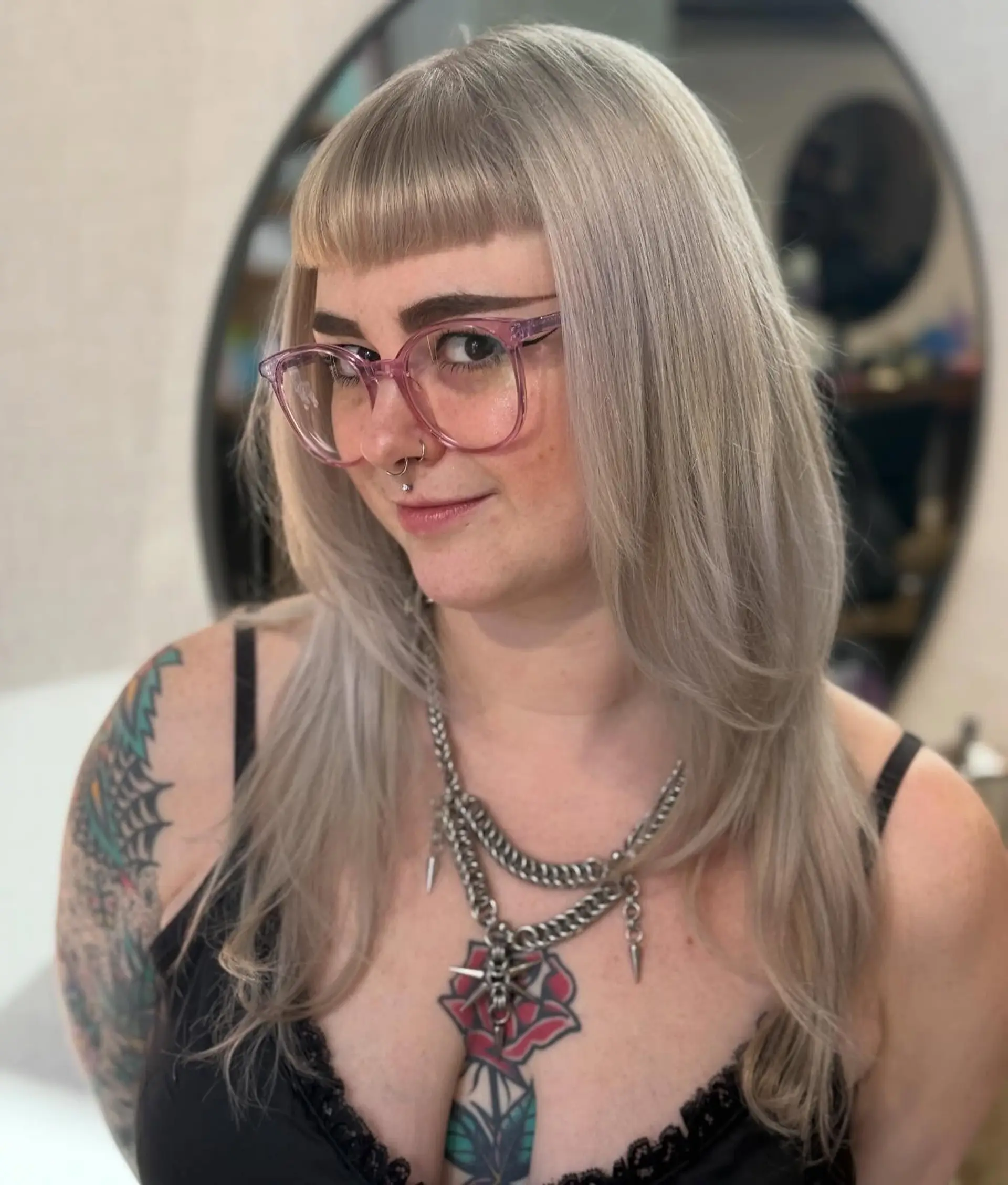 Long ash-toned blonde hair cut with face-framing layers and a blunt micro fringe. 1
