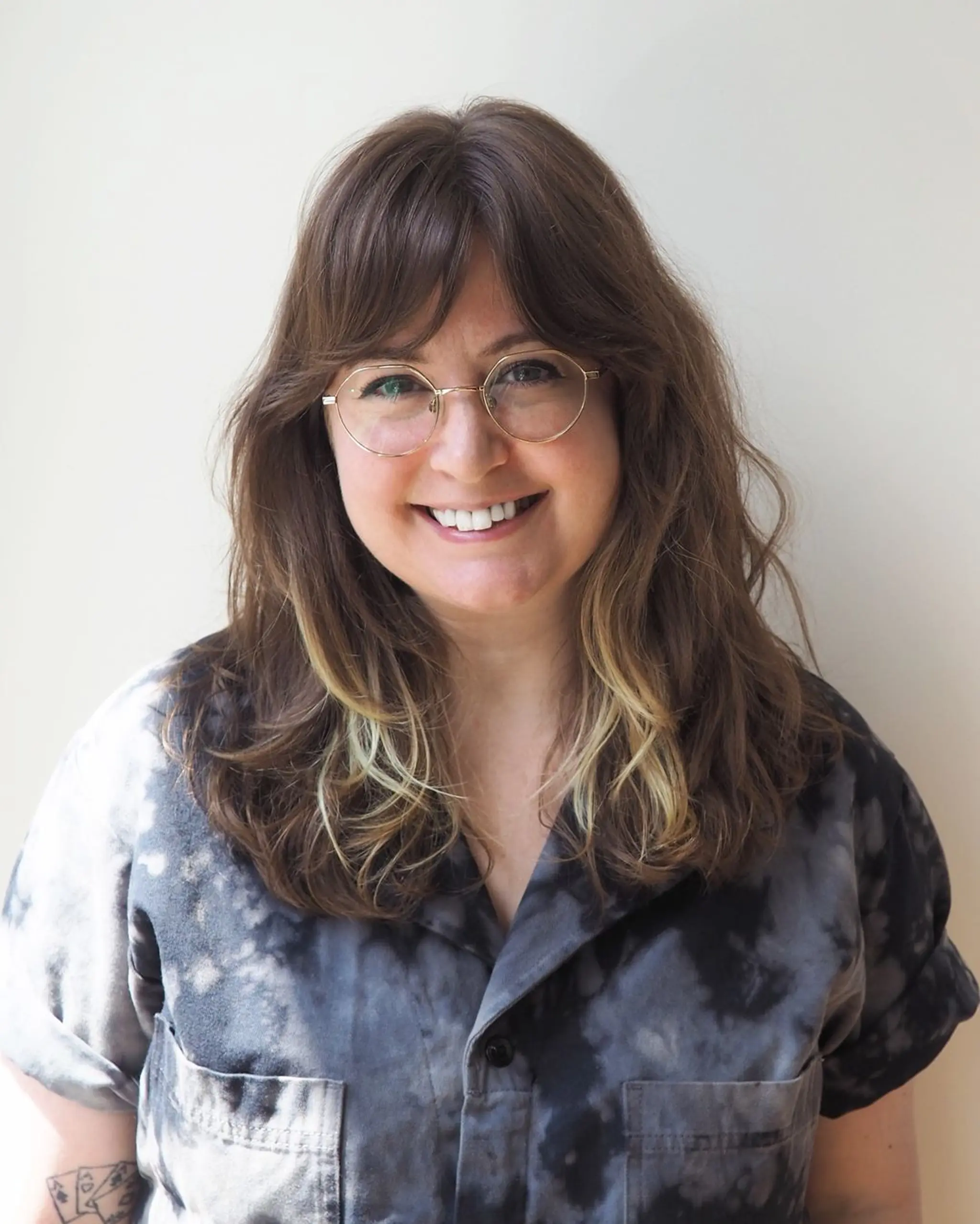 A medium-length wavy hairstyle with brown hair and blonde face-framing highlights. The textured layers and natural waves create a relaxed, cascading effect.