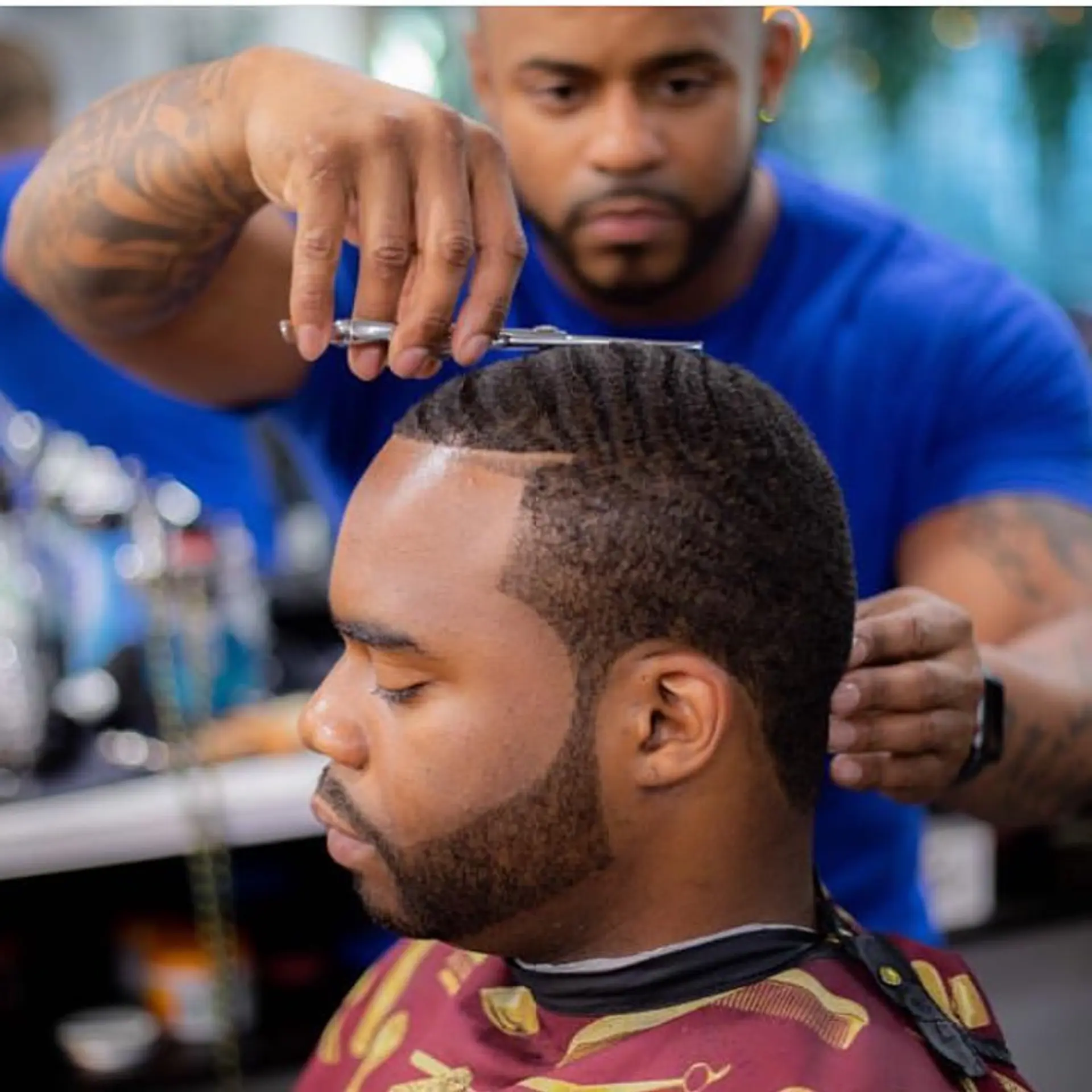 A clean, short buzz haircut featuring defined waves on top with an ultra-crisp line up and groomed beard. 1