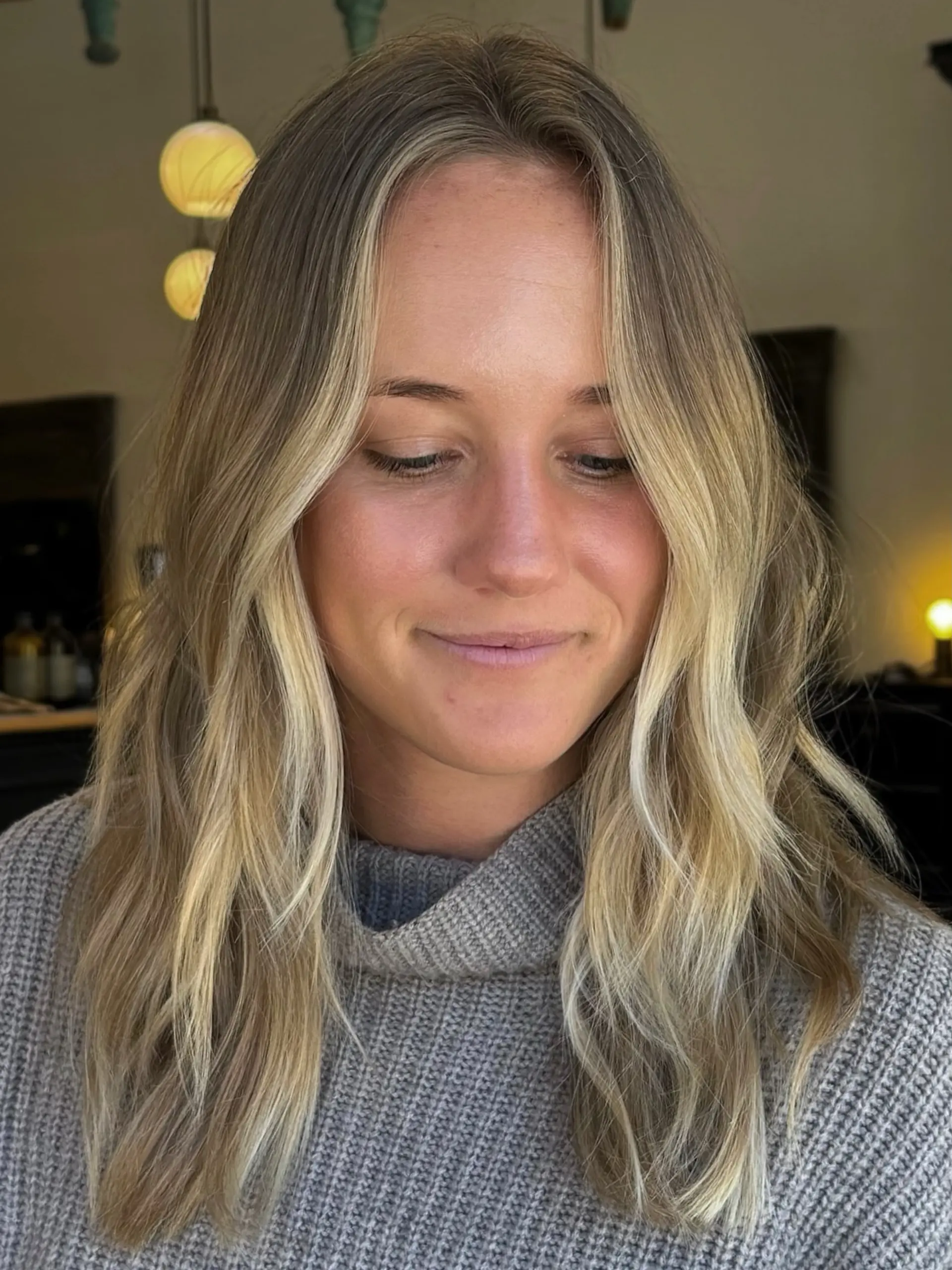 Medium-to-long textured hair styled with soft waves and bright, dimensional blonde highlights framing the face. 1